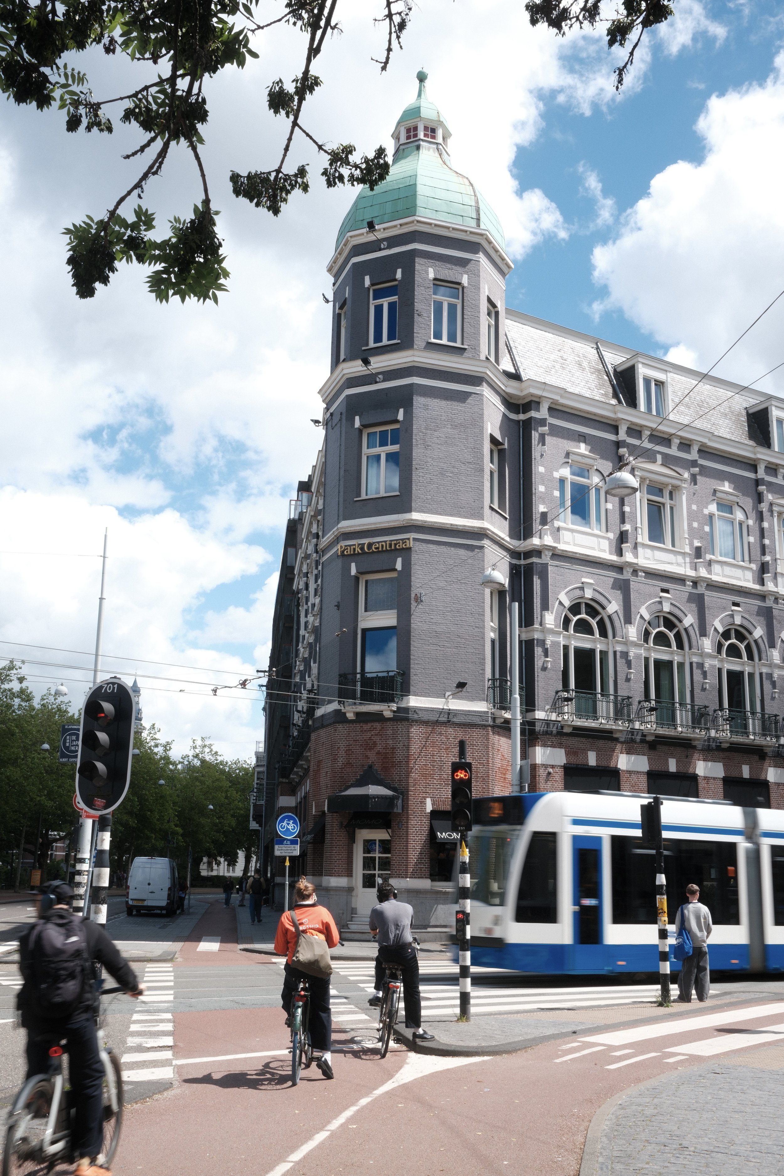 Park Centraal Amsterdam overlooking a vibrant city street with cyclists and tram passing by