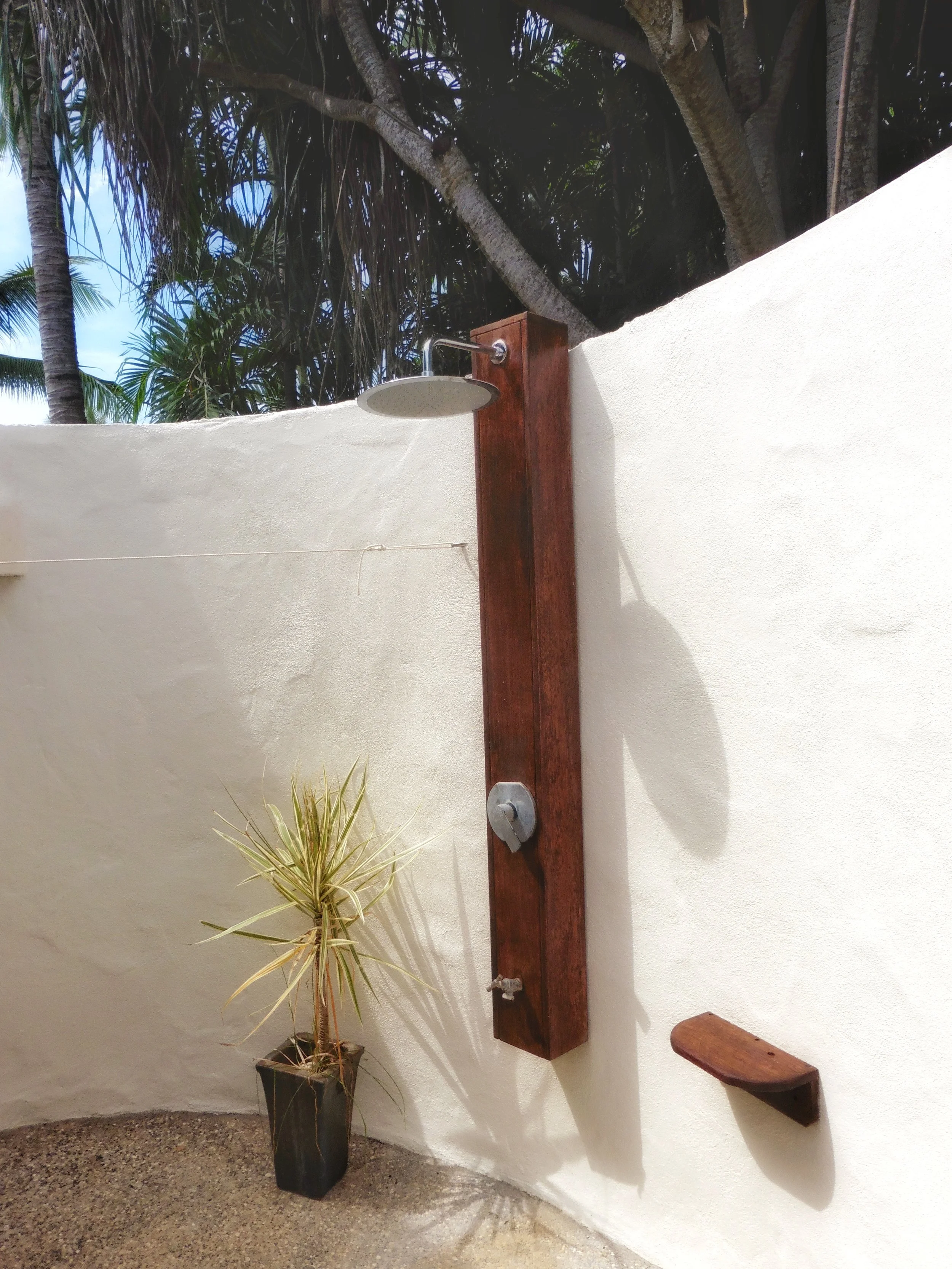 Private outdoor tropical shower surrounded by lush greenery and island-inspired design