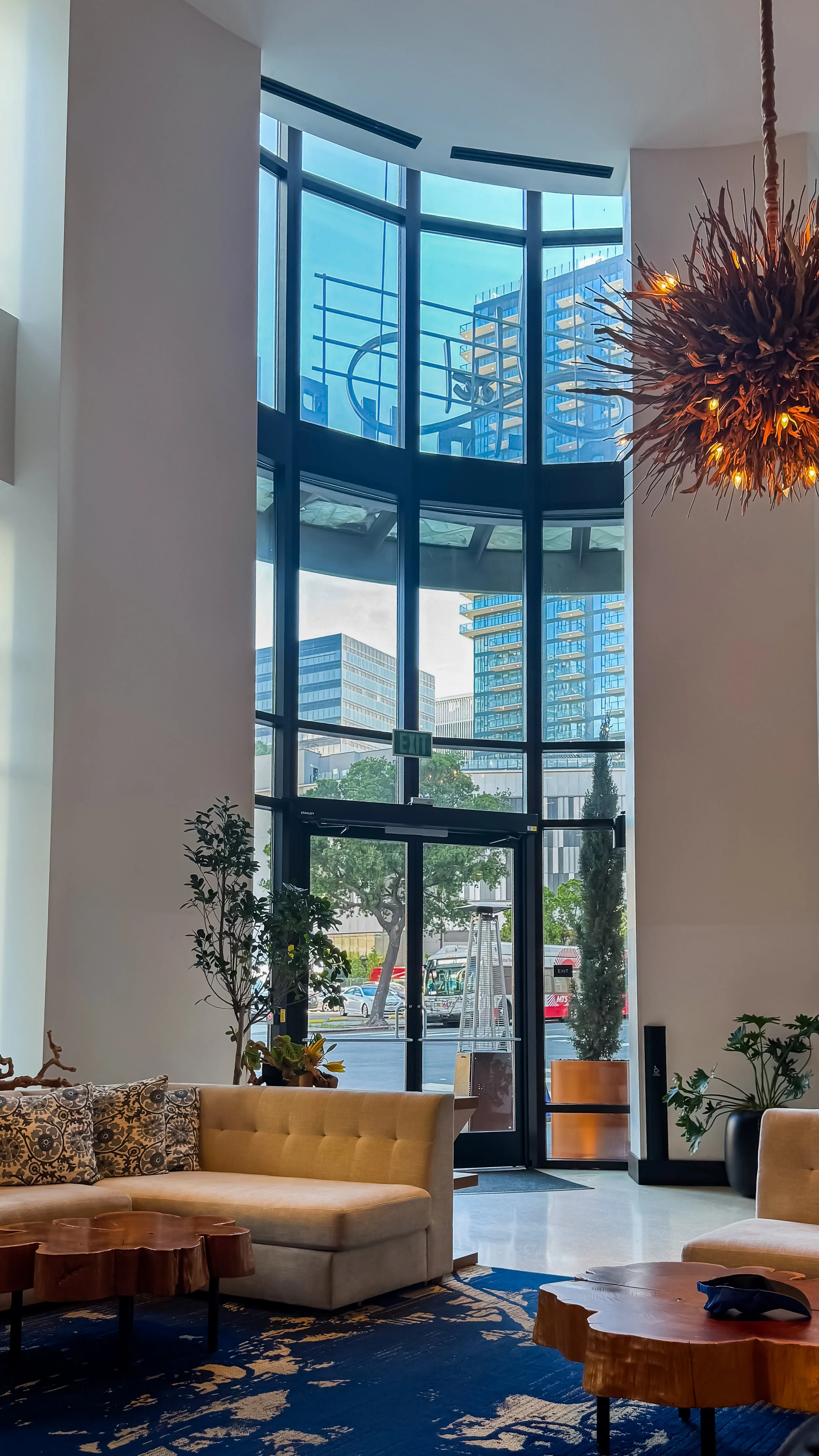 Bright double-height lobby with floor-to-ceiling windows, designer furnishings, and abundant natural light