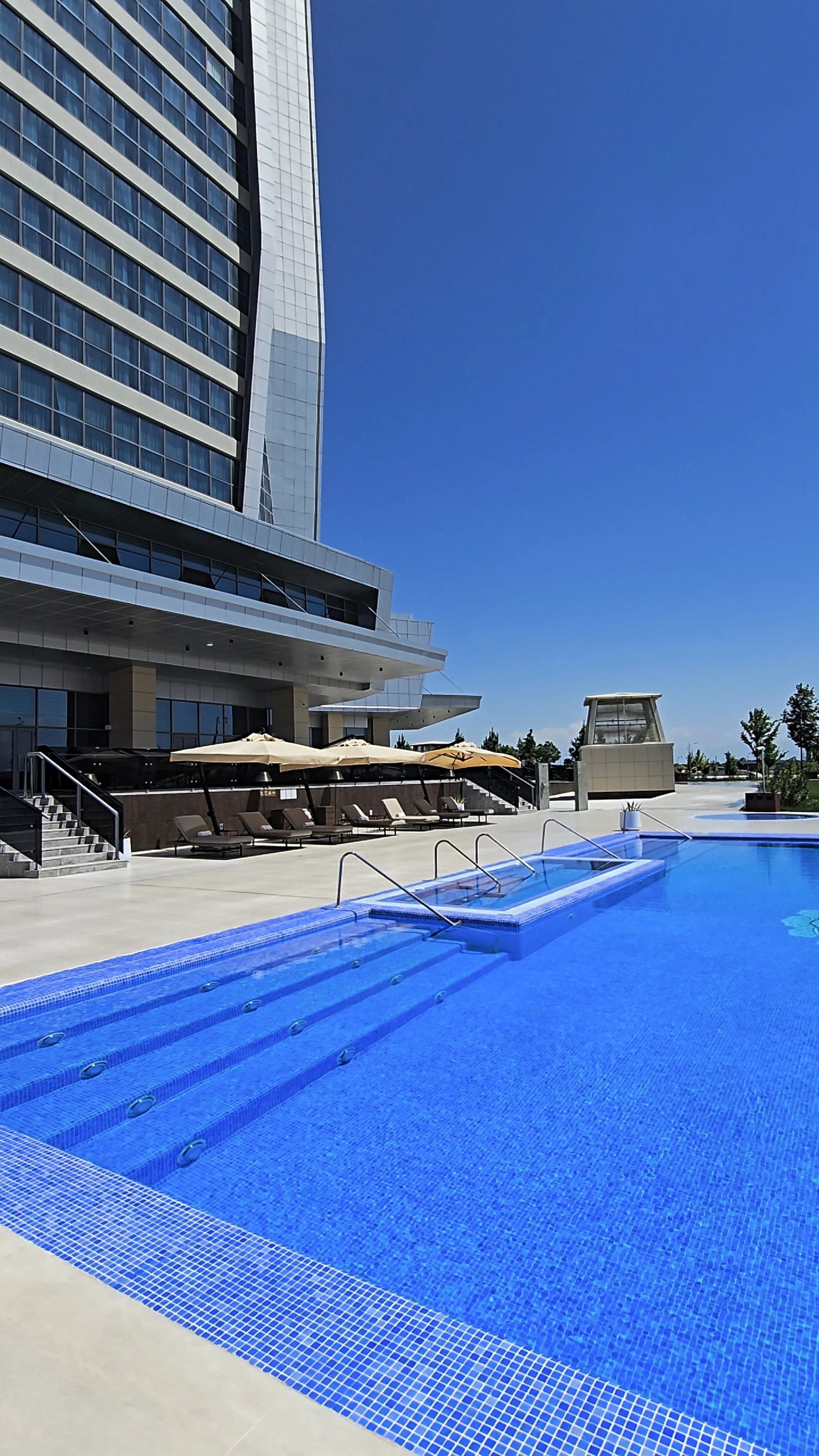 Outdoor swimming pool surrounded by contemporary architecture and spacious sun loungers