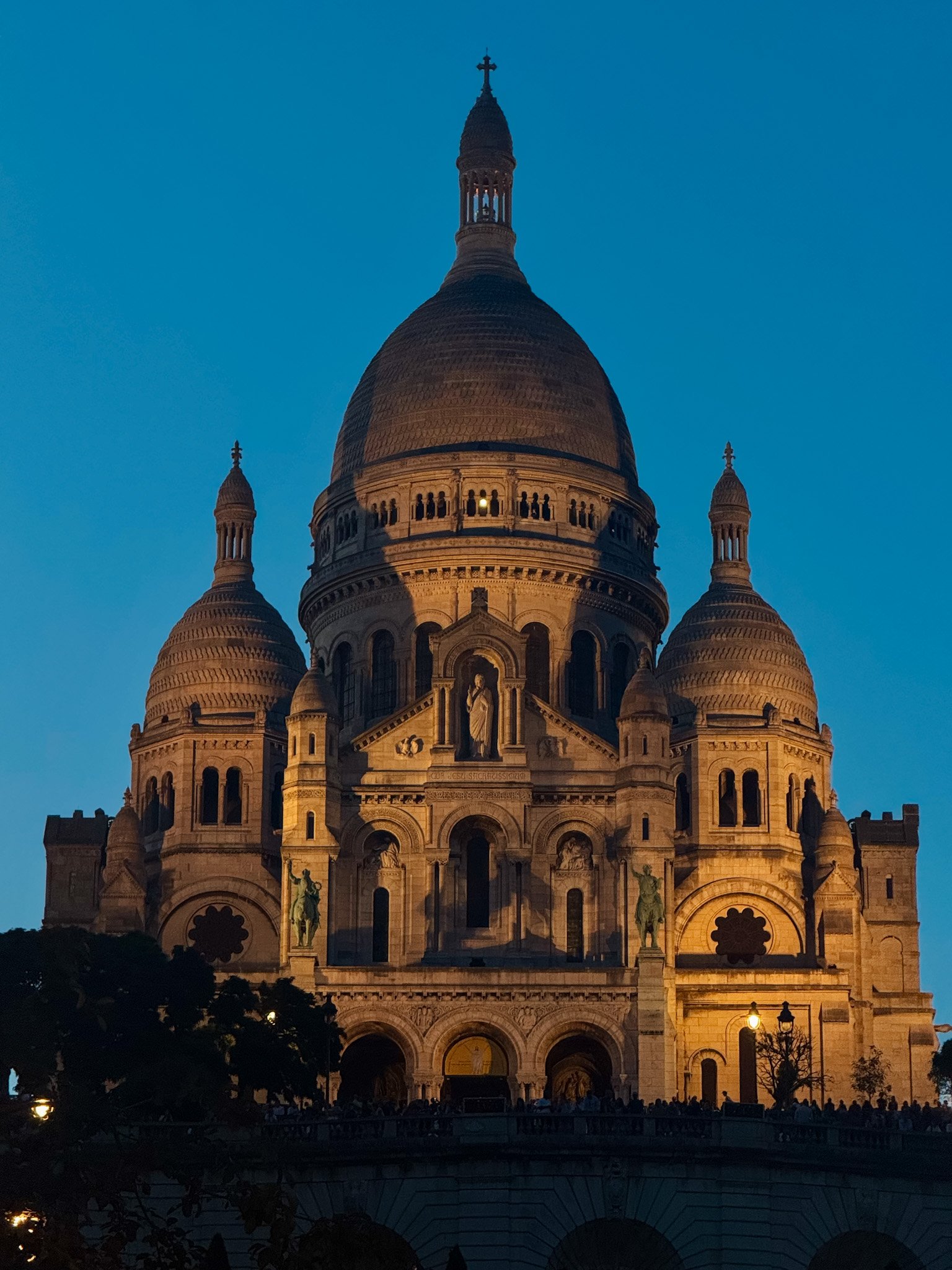 Sacré Cœur Basilica illuminated at dusk overlooking the Paris skyline