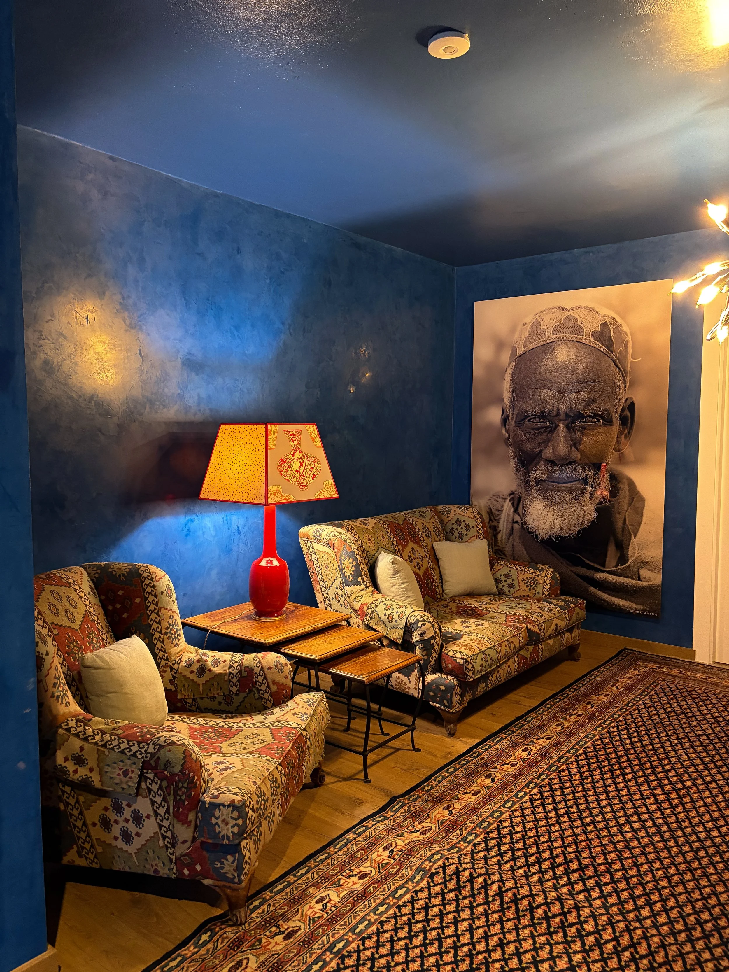 Elegant lounge featuring deep blue walls, patterned armchairs, and warm lighting