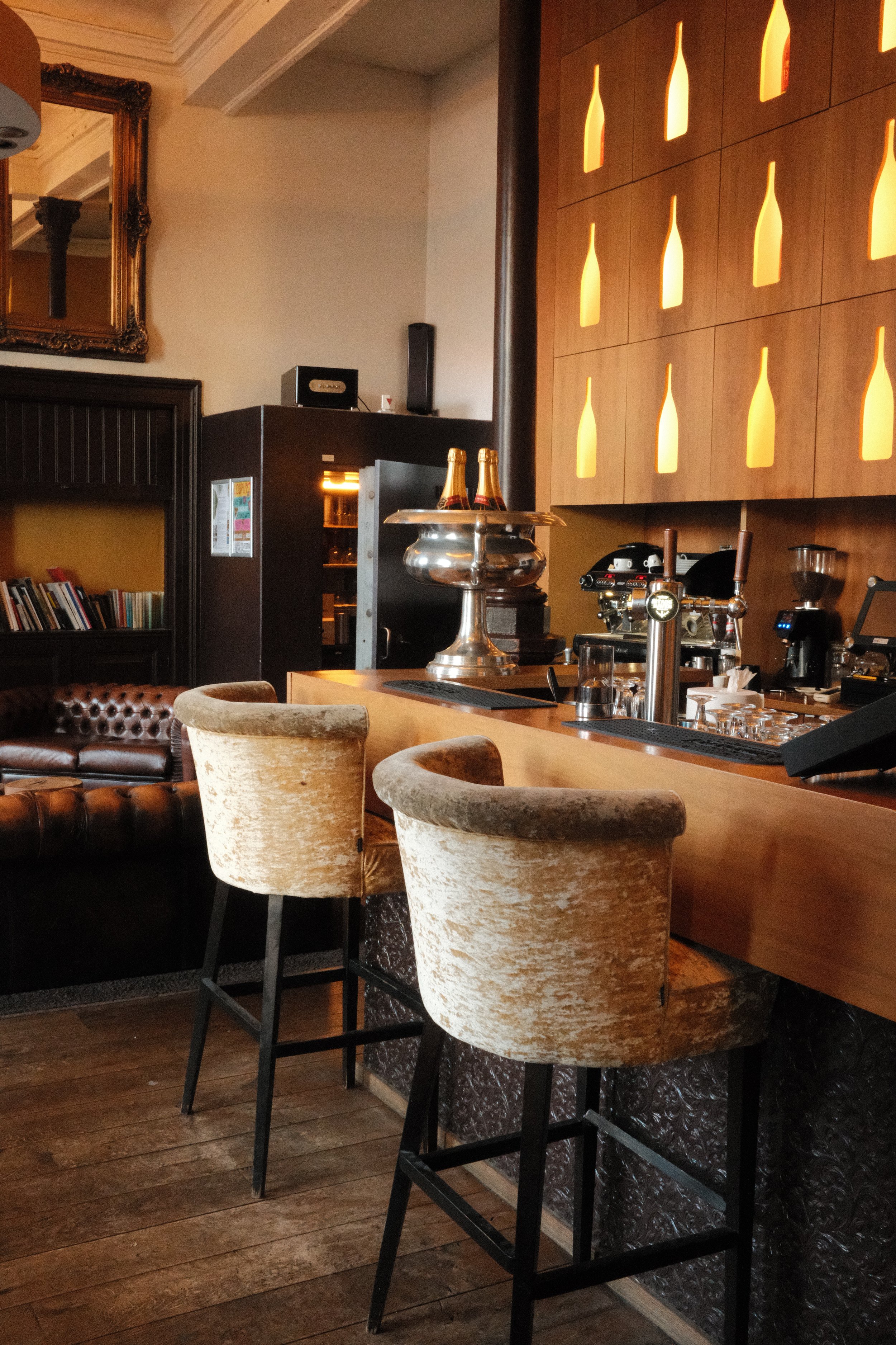 Stylish hotel bar with leather seating, champagne display, and warm lighting at Suite Hotel Pincoffs Rotterdam