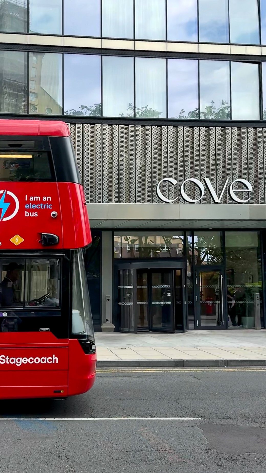 Modern aparthotel entrance in Canary Wharf beside London’s iconic red double-decker bus