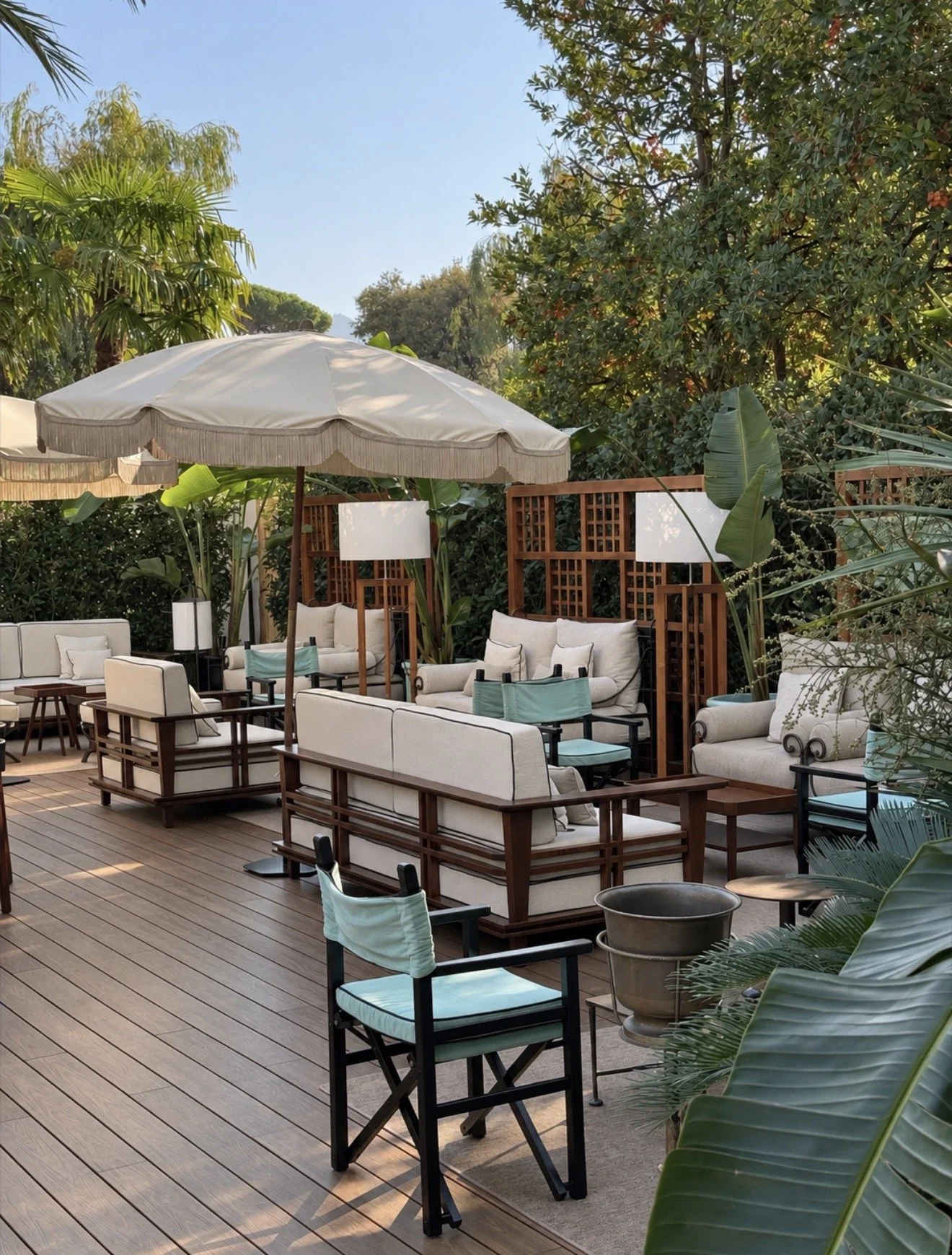 Peaceful garden terrace with cushioned lounge seating, parasols, and abundant Mediterranean greenery