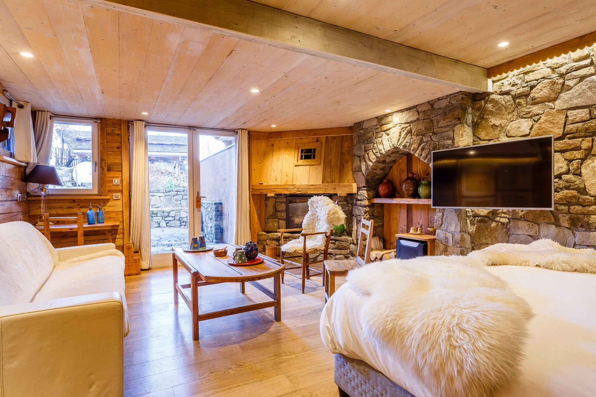 Spacious suite with exposed stone walls and modern fireplace at Le Hameau de Mon Père – Les Gets, France