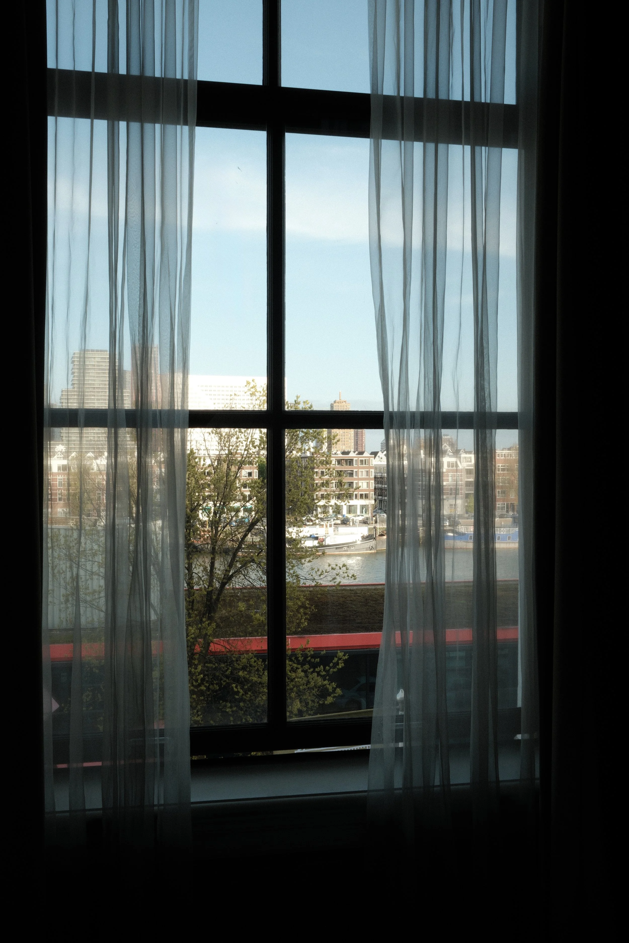 Harbour view through large windows overlooking Rotterdam’s historic waterfront from the guest room