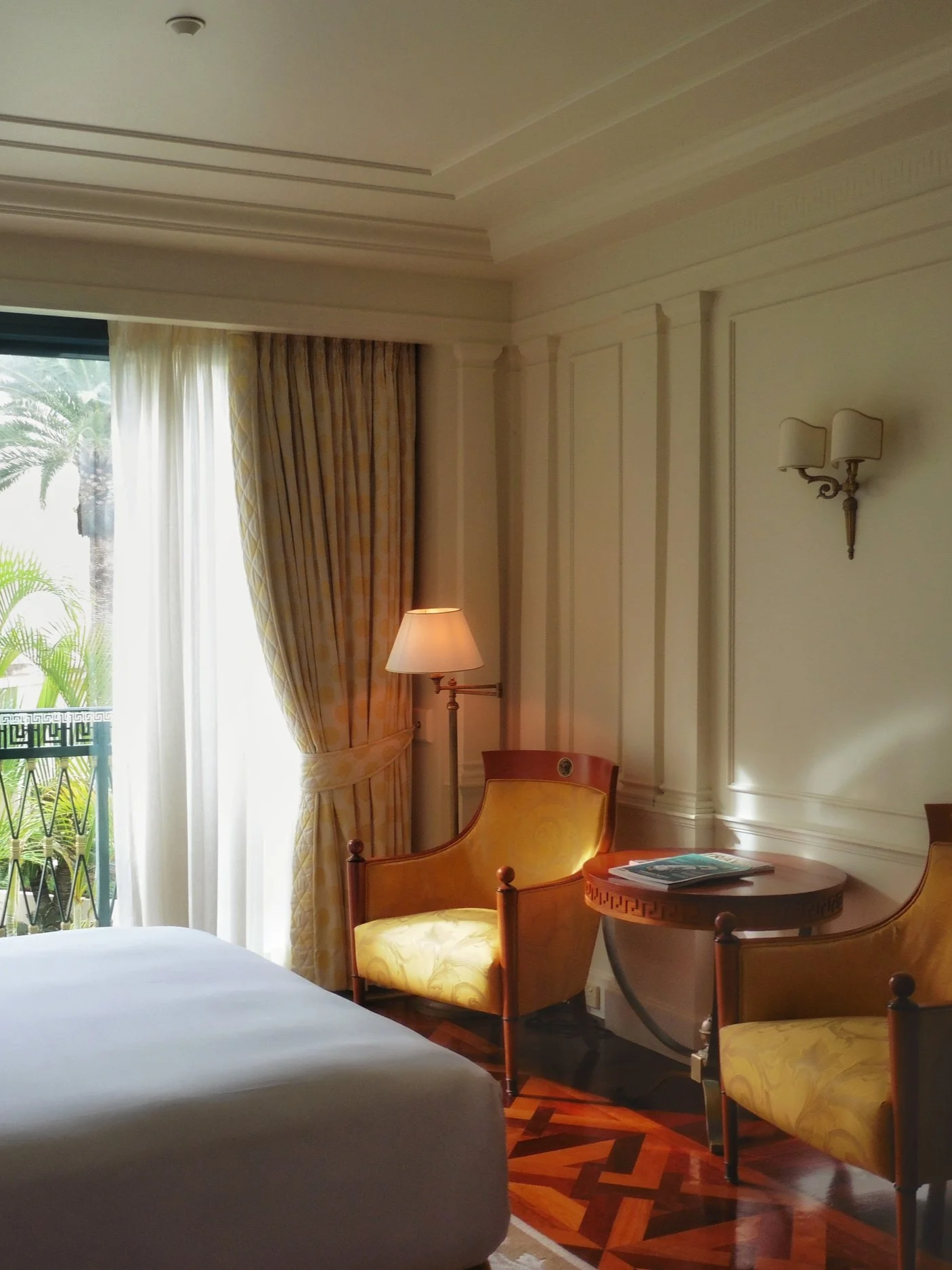 Bright luxury guest room with private balcony overlooking tropical resort gardens