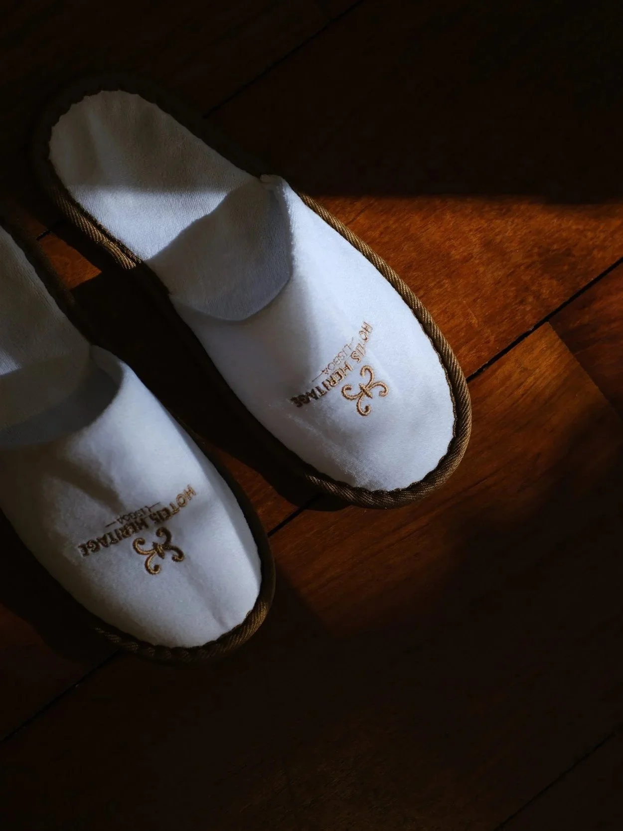 Soft branded slippers placed on warm wooden flooring with natural morning light