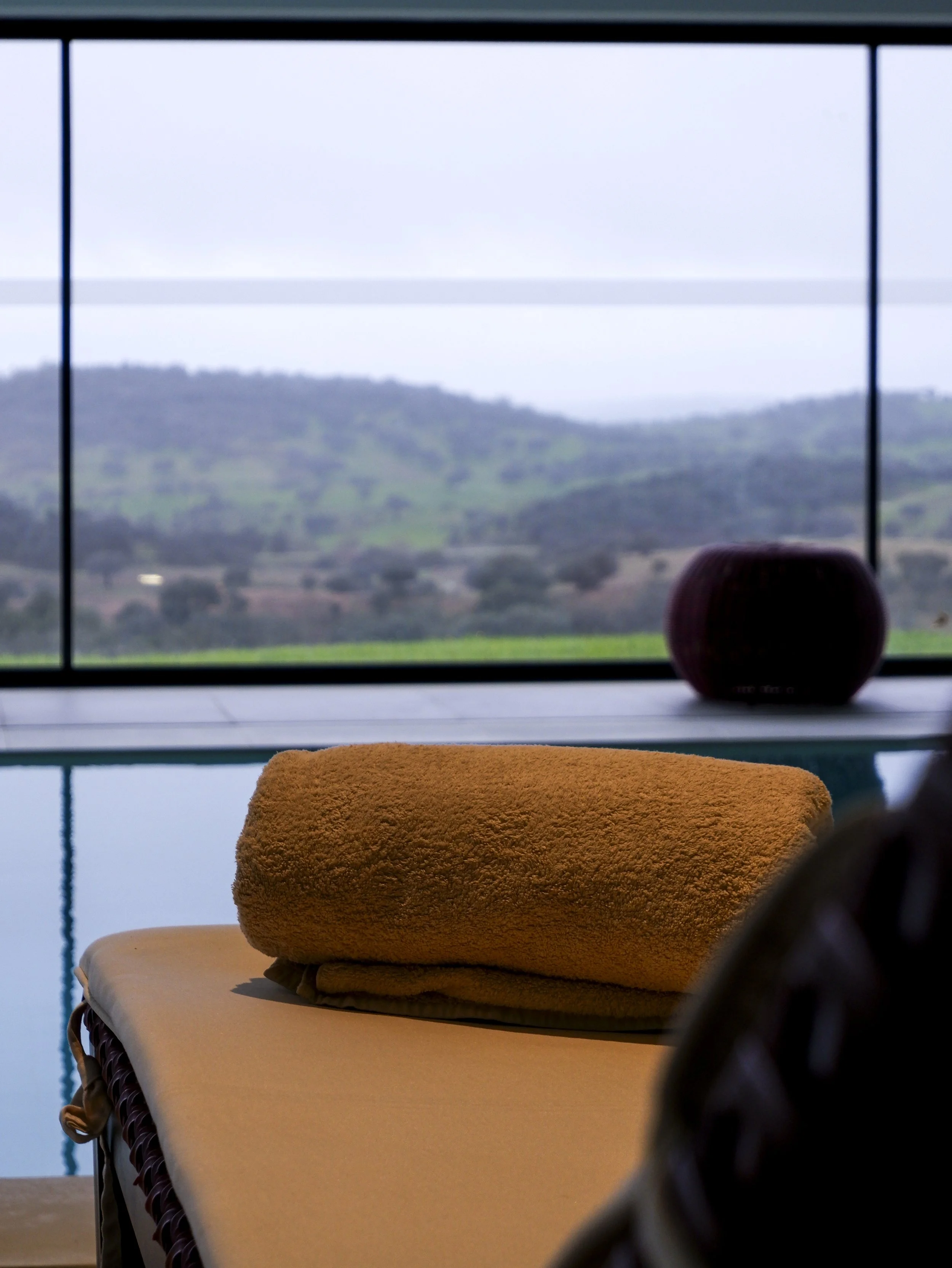 Indoor spa pool with soft natural light and panoramic countryside views through floor-to-ceiling windows, creating a calm wellness retreat, Land of Alandroal – Alandroal, Portugal.