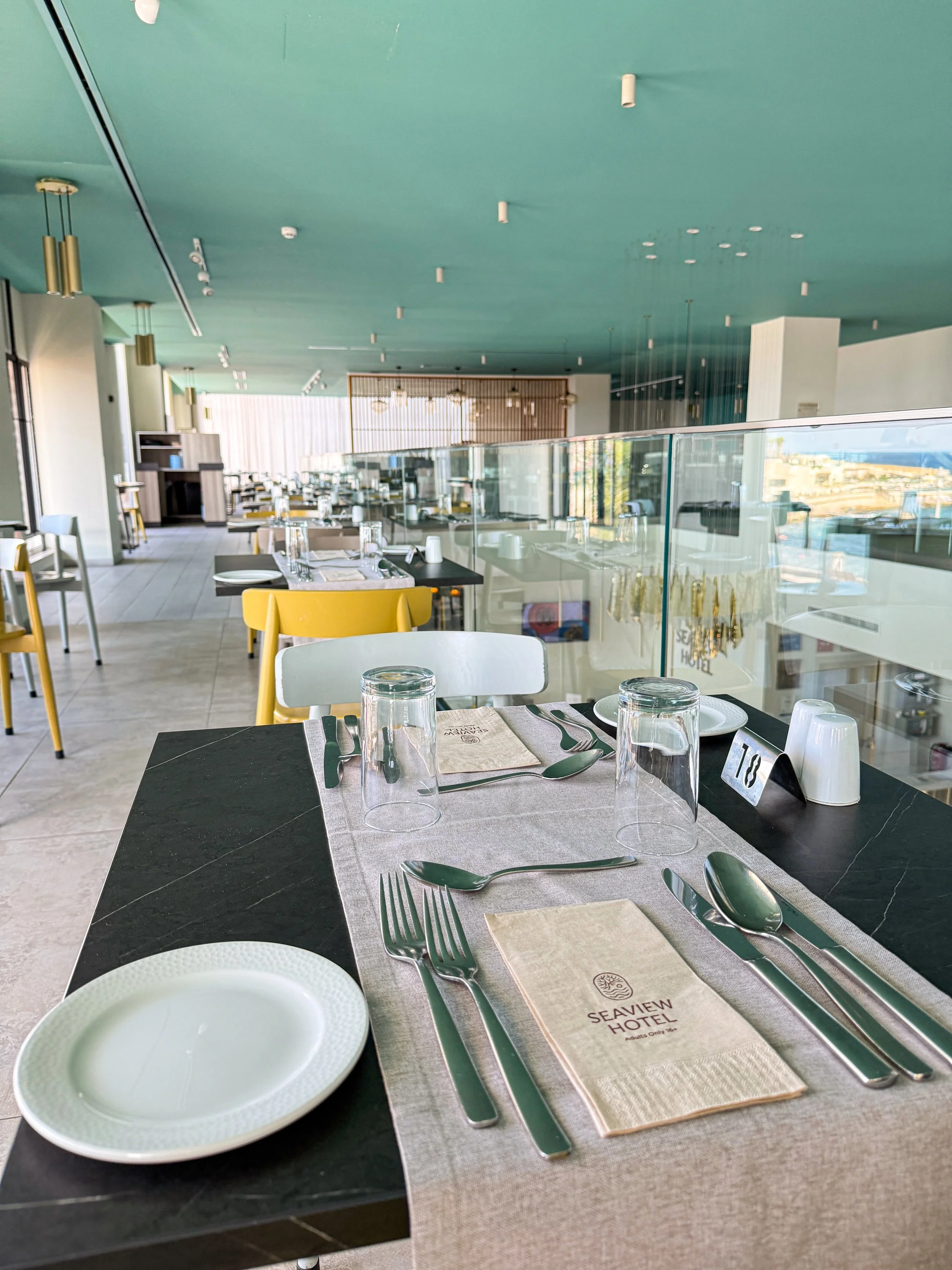 Contemporary restaurant with elegant table settings, colorful seating, and panoramic windows
