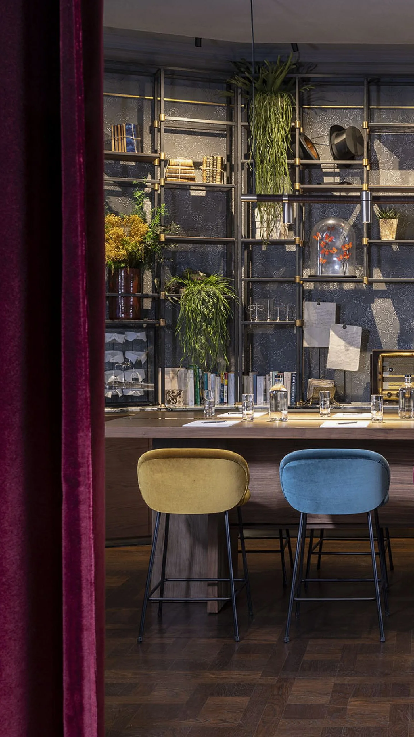 Elegant library lounge with designer shelving, velvet seating, and botanical décor