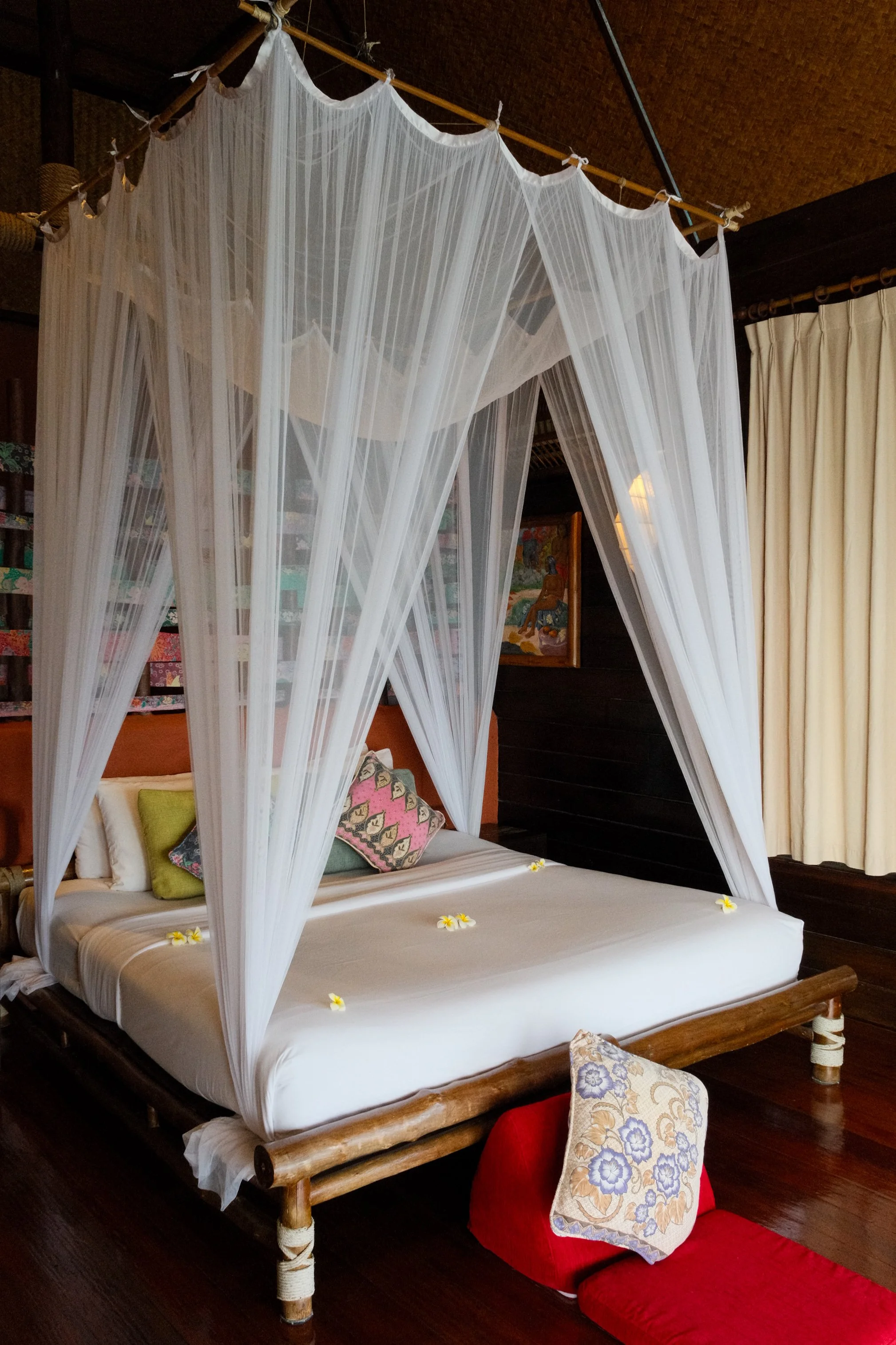 Romantic bamboo bed with a flowing mosquito net, floral details, and warm wooden interiors