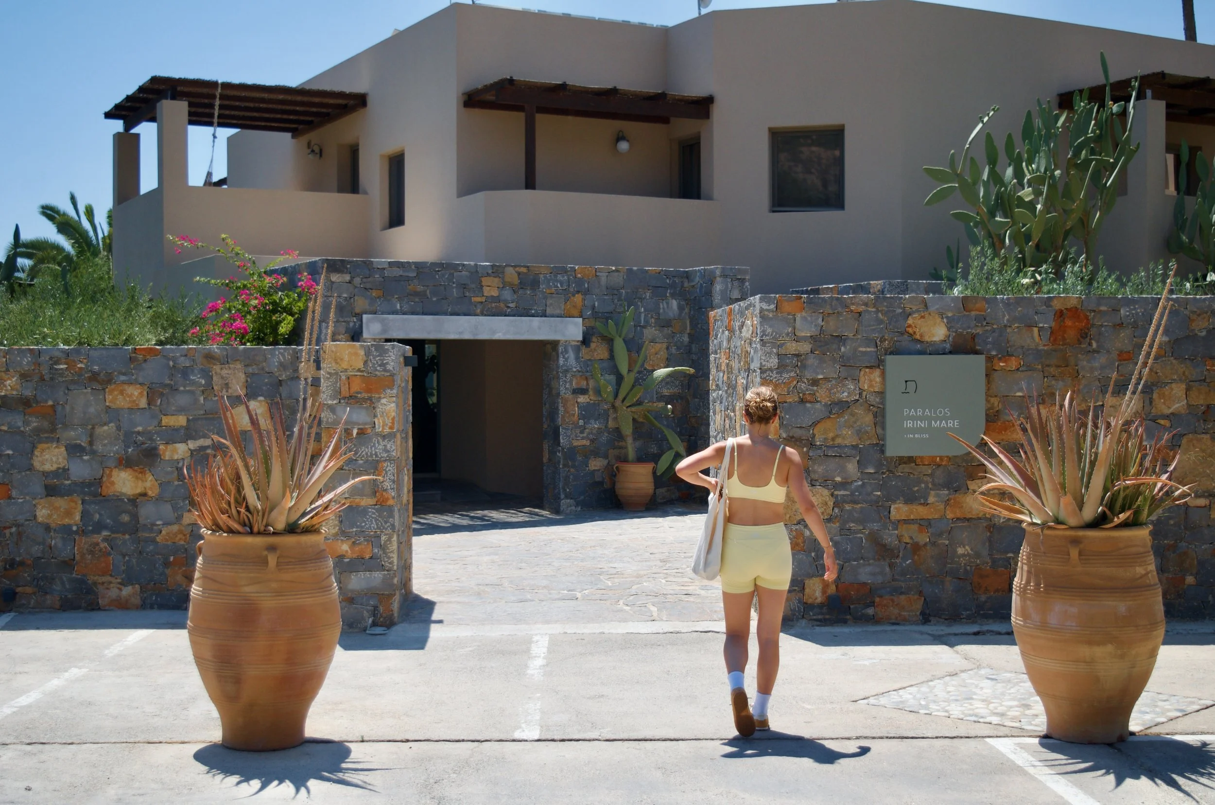 Welcoming entrance framed by natural stone walls, terracotta pots, and Mediterranean landscaping