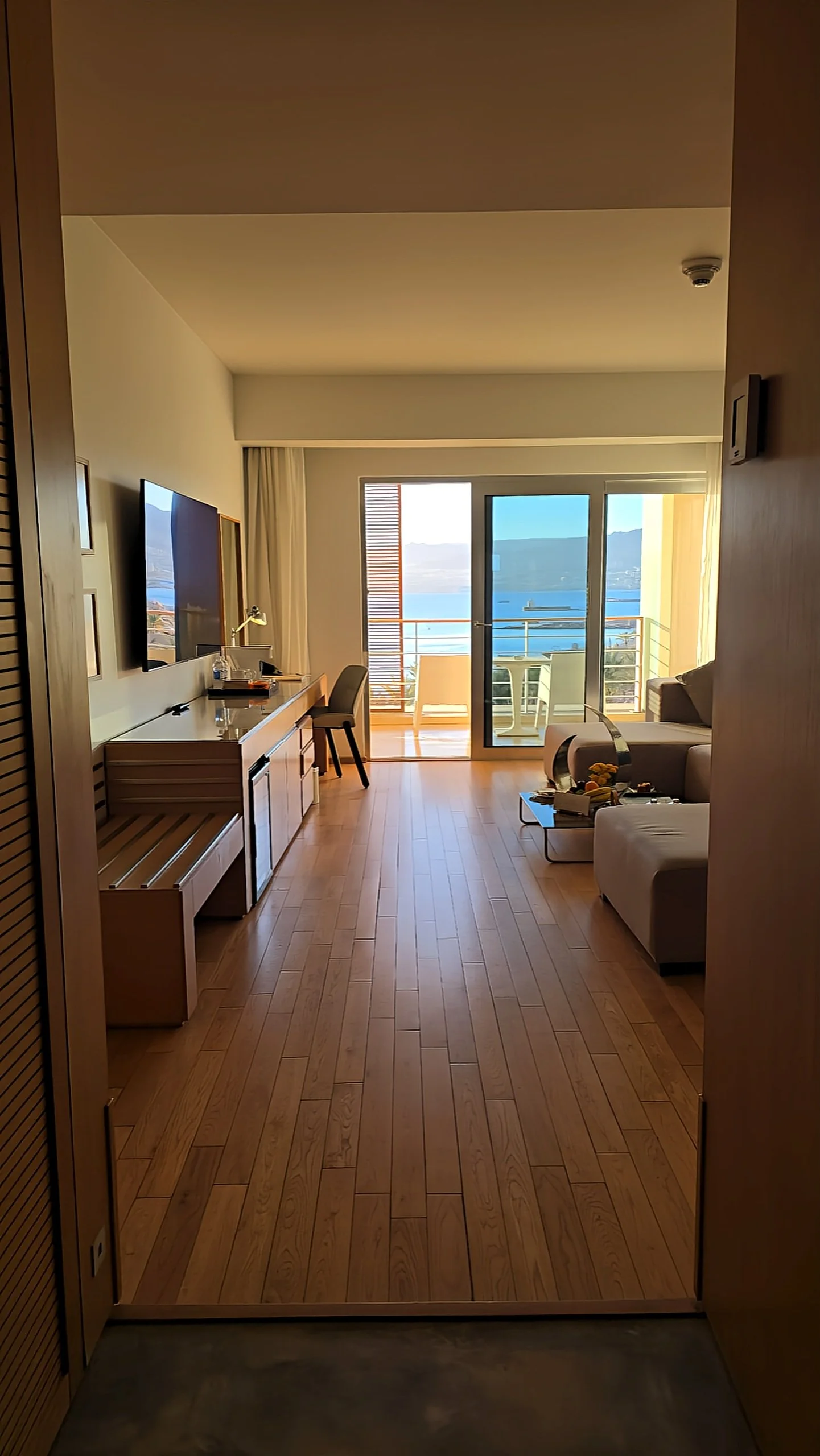 Spacious suite with desk, lounge area, and balcony opening to panoramic Red Sea views and distant mountains, Kempinski Hotel Aqaba Red Sea – Aqaba, Jordan.