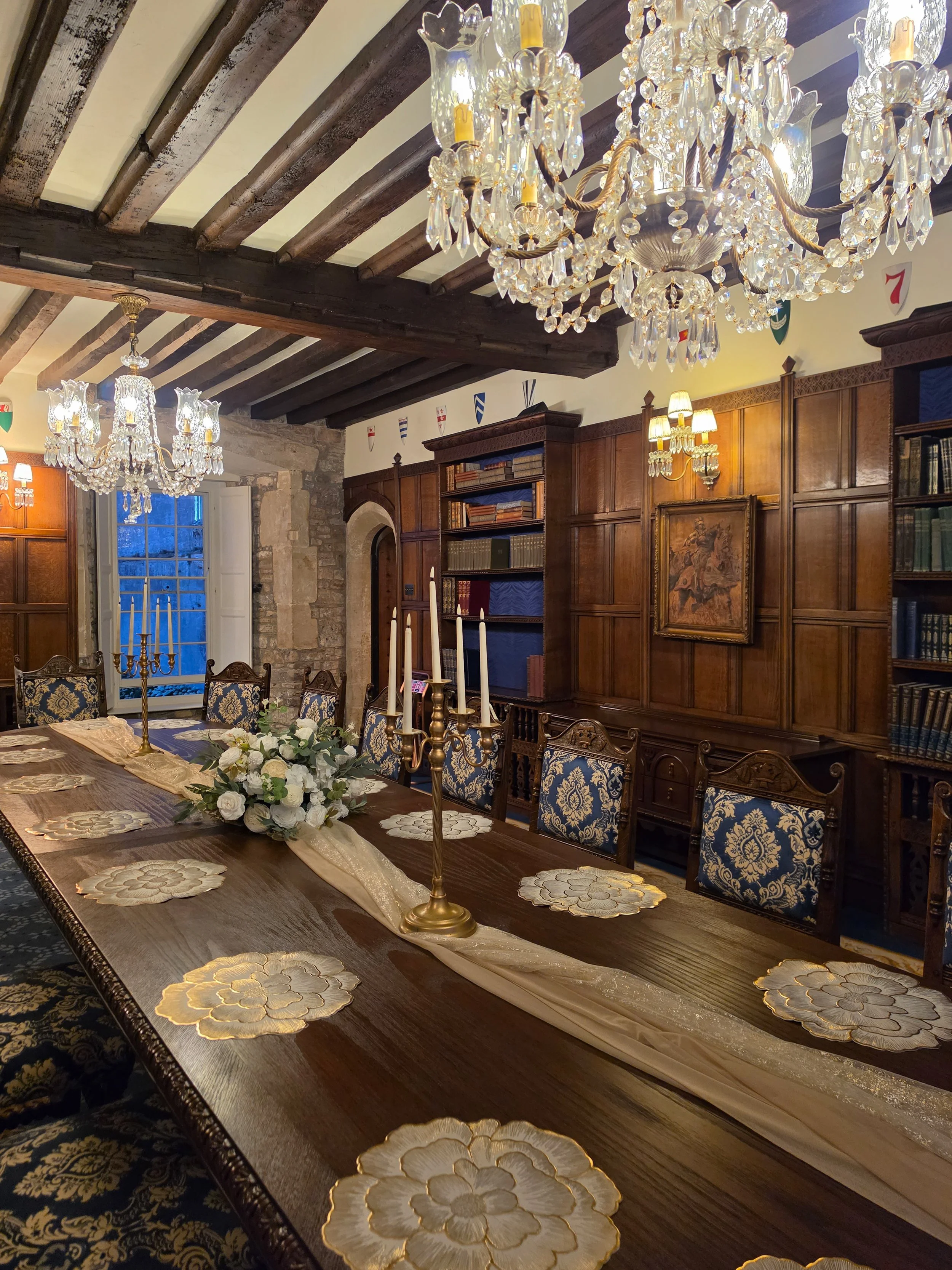 Grand medieval dining hall featuring crystal chandeliers, oak beams, and historic castle interiors