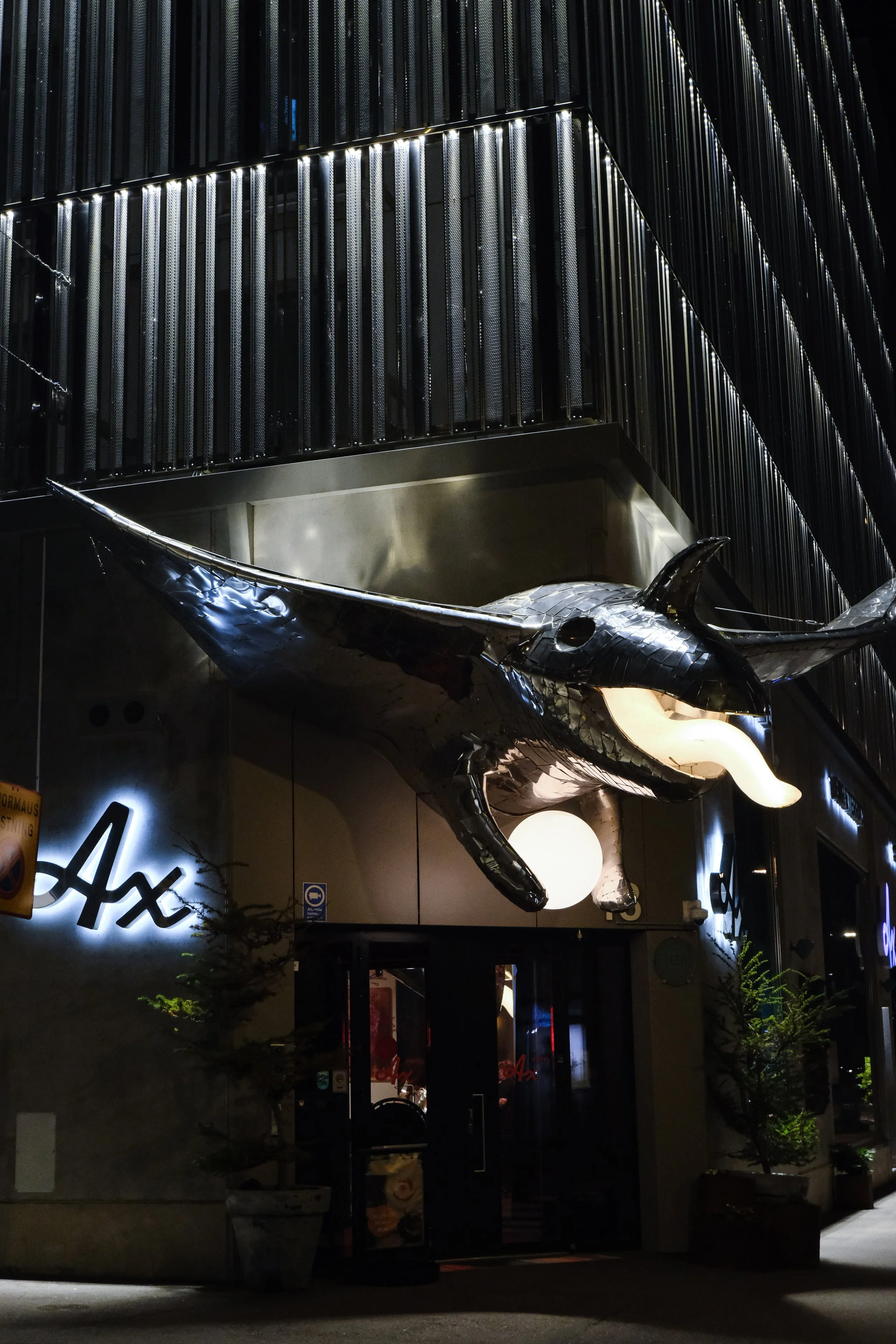 Hotel AX entrance illuminated at night beneath the iconic whale sculpture