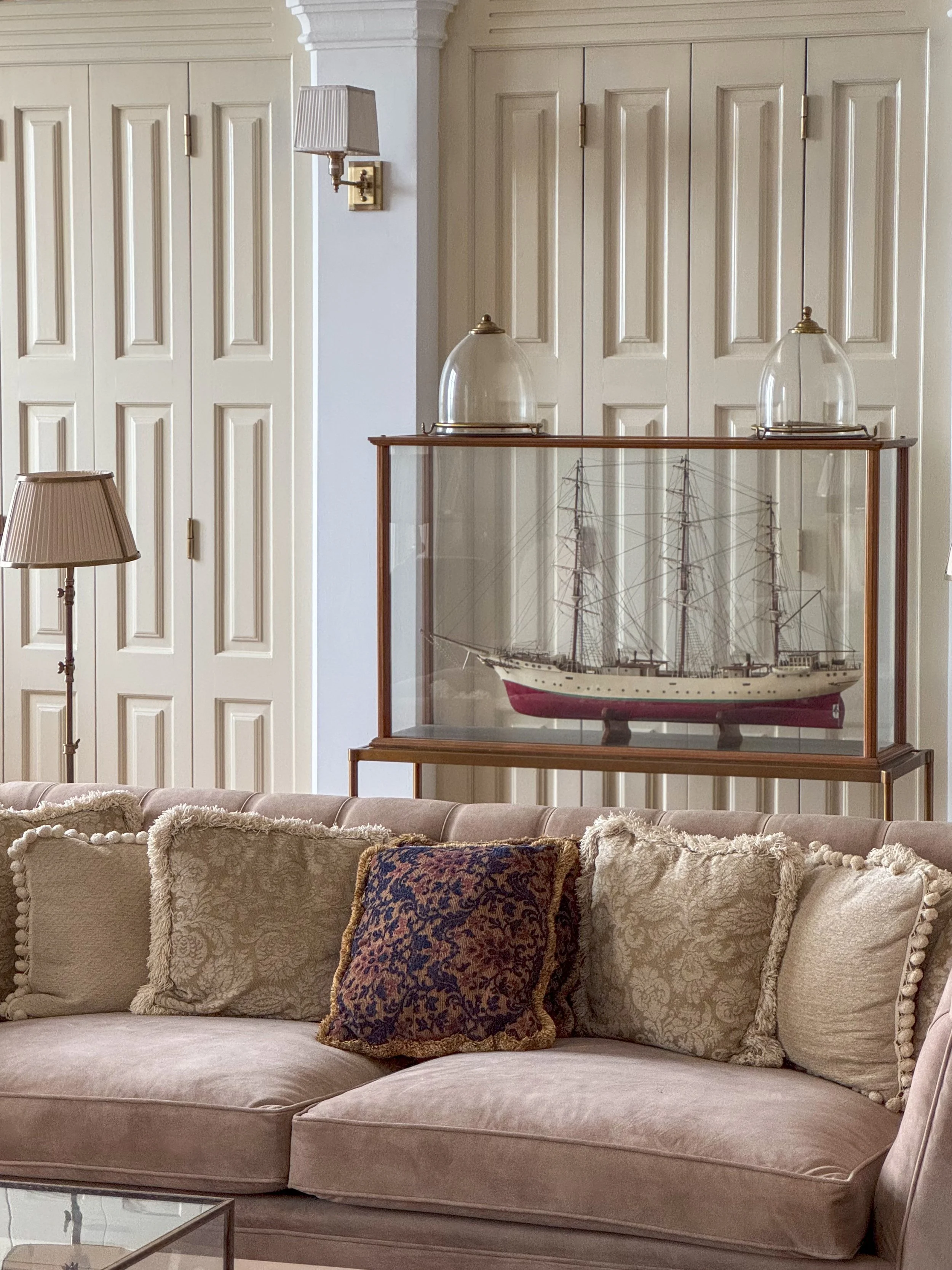 A classic sitting room detail pairs soft upholstery with a maritime model ship