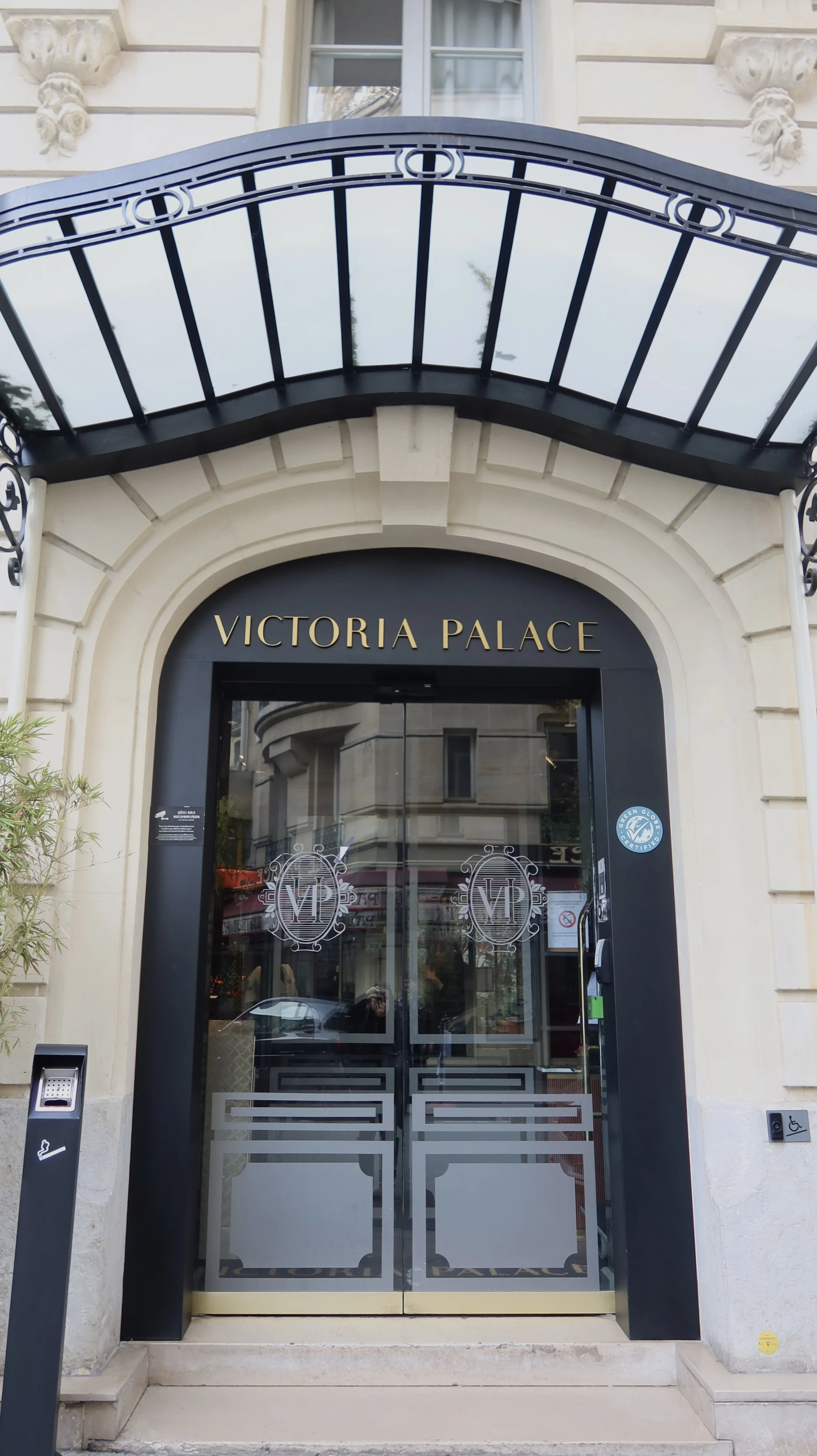 Elegant Parisian entrance with black canopy and classic stone façade on a quiet city street, Victoria Palace Hotel – Paris, France.