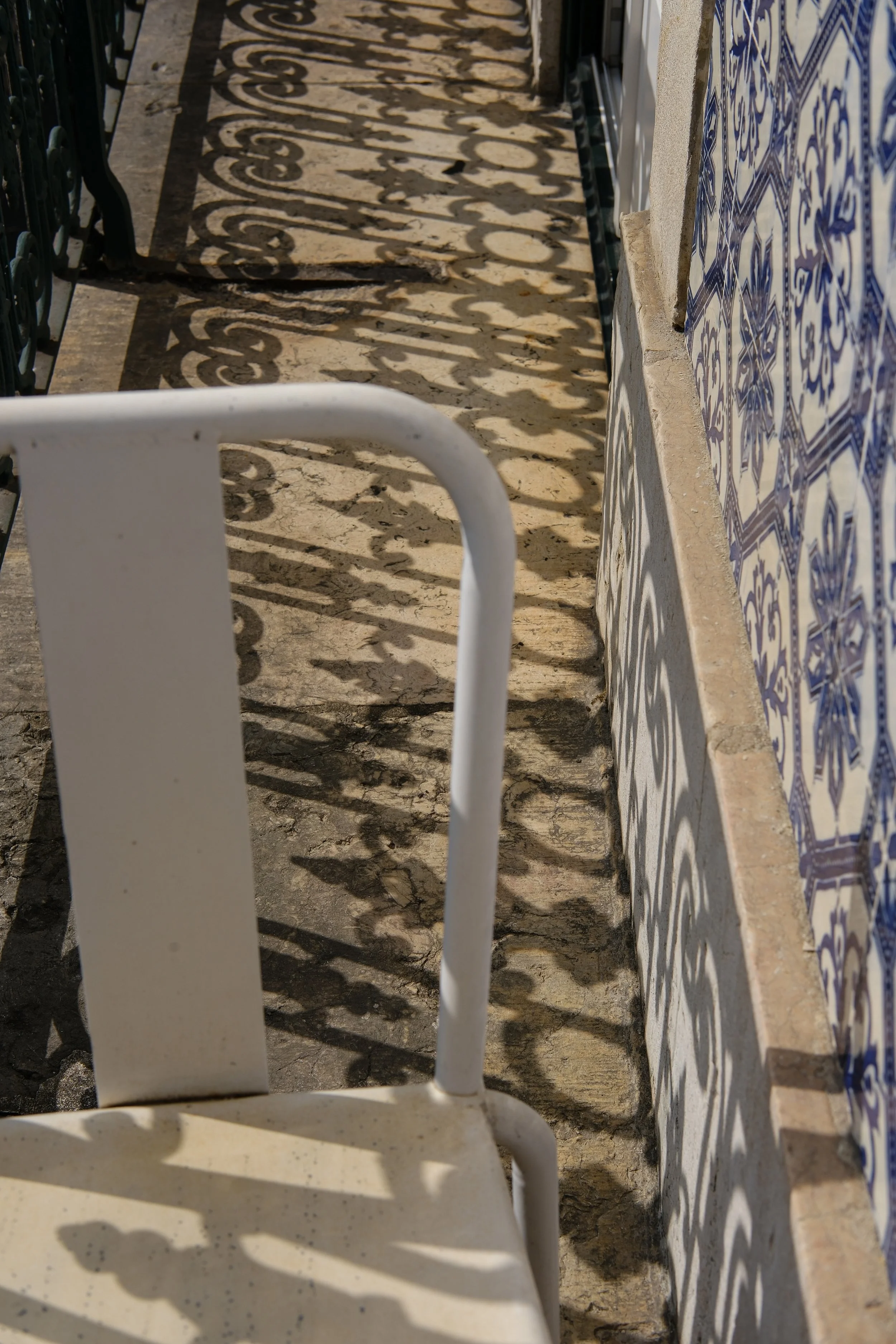 Sunlight casting elegant shadows across handcrafted Portuguese tiles and balcony