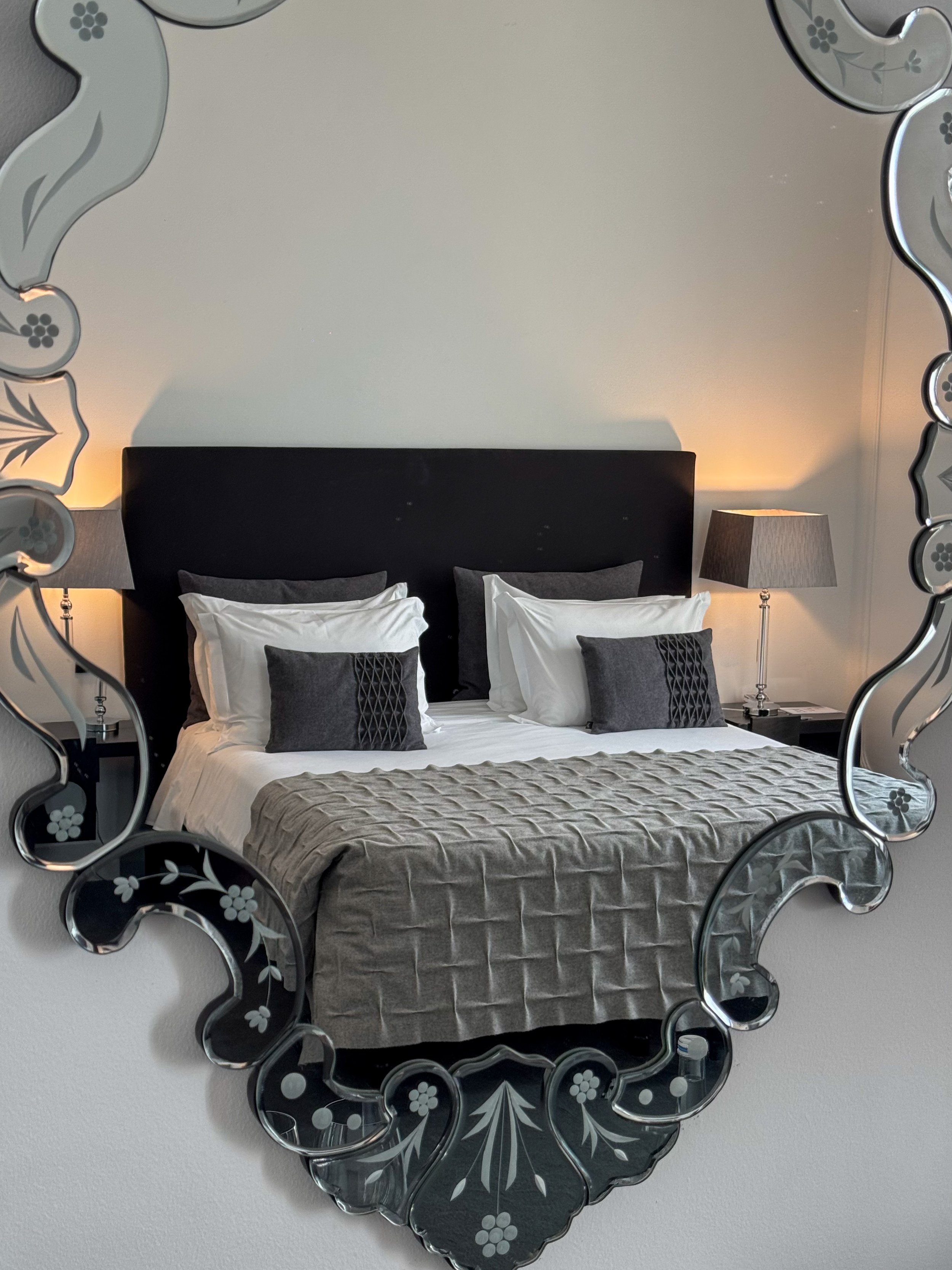 Elegant guest room reflected through a handcrafted decorative mirror
