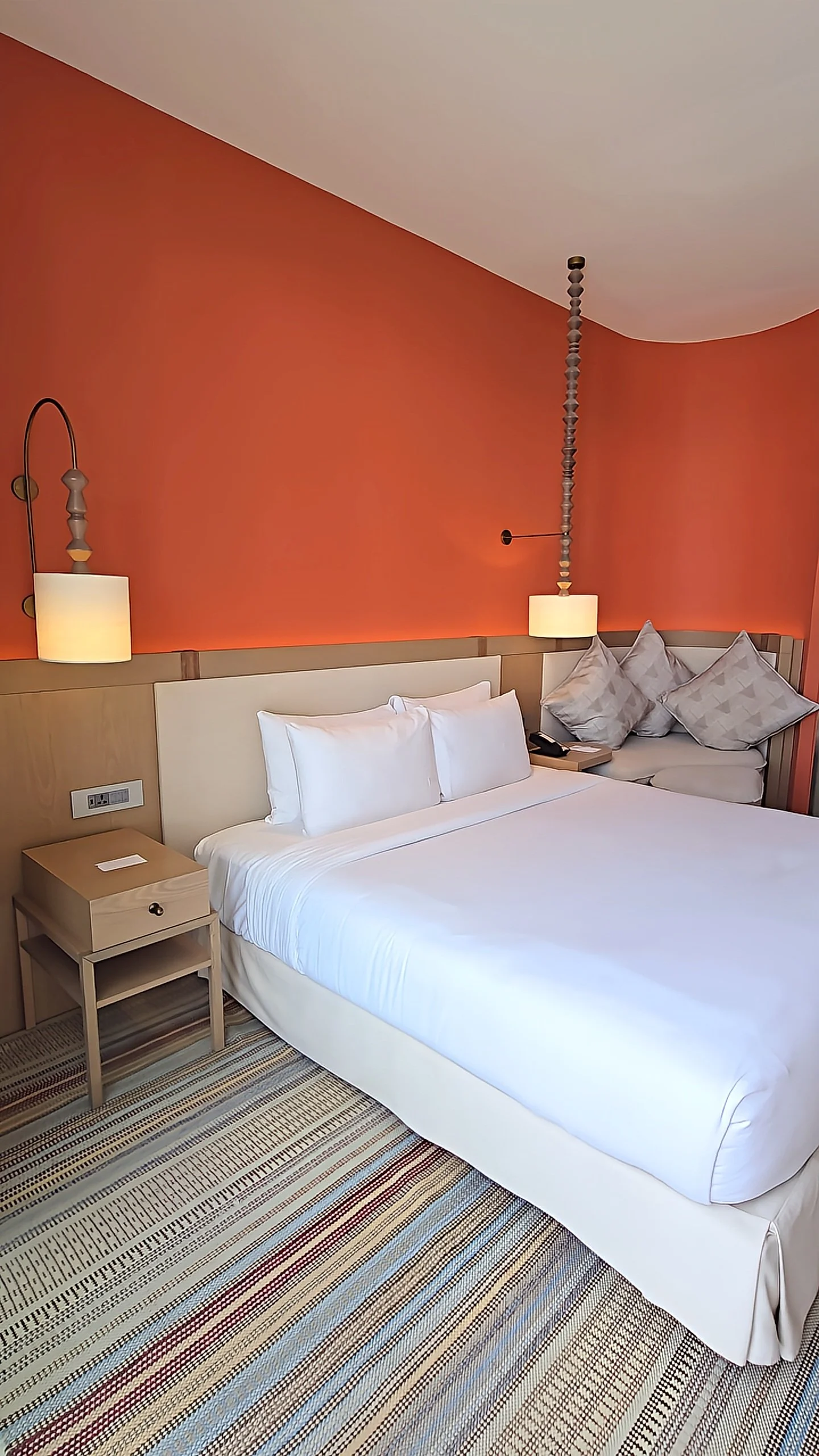 Contemporary guest room with coral accent wall, soft lighting, and minimalist design details, Hyatt Regency Aqaba Ayla Resort – Aqaba, Jordan.