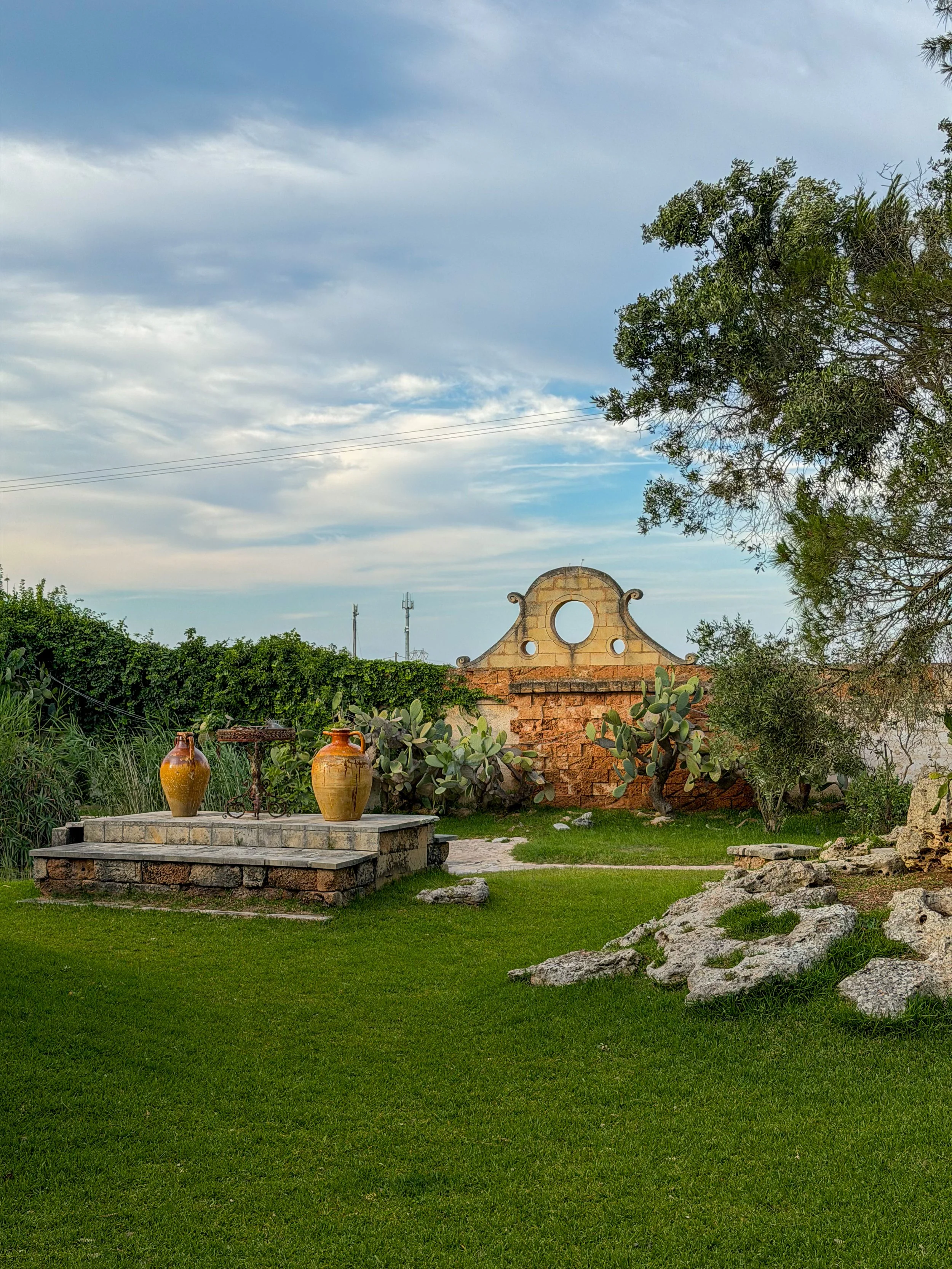 Peaceful garden spaces with traditional stone details and Mediterranean vegetation throughout Tenute Al Bano