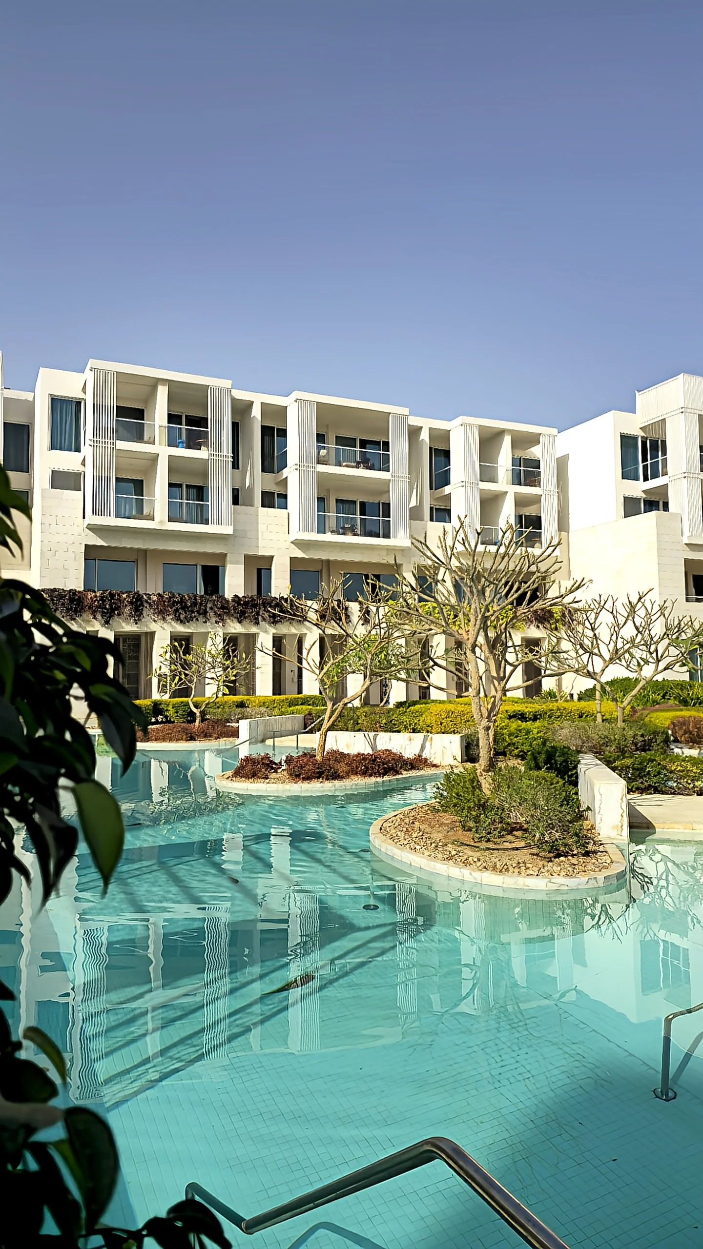 Modern resort buildings reflected in tranquil lagoon-style swimming pools and landscaped gardens