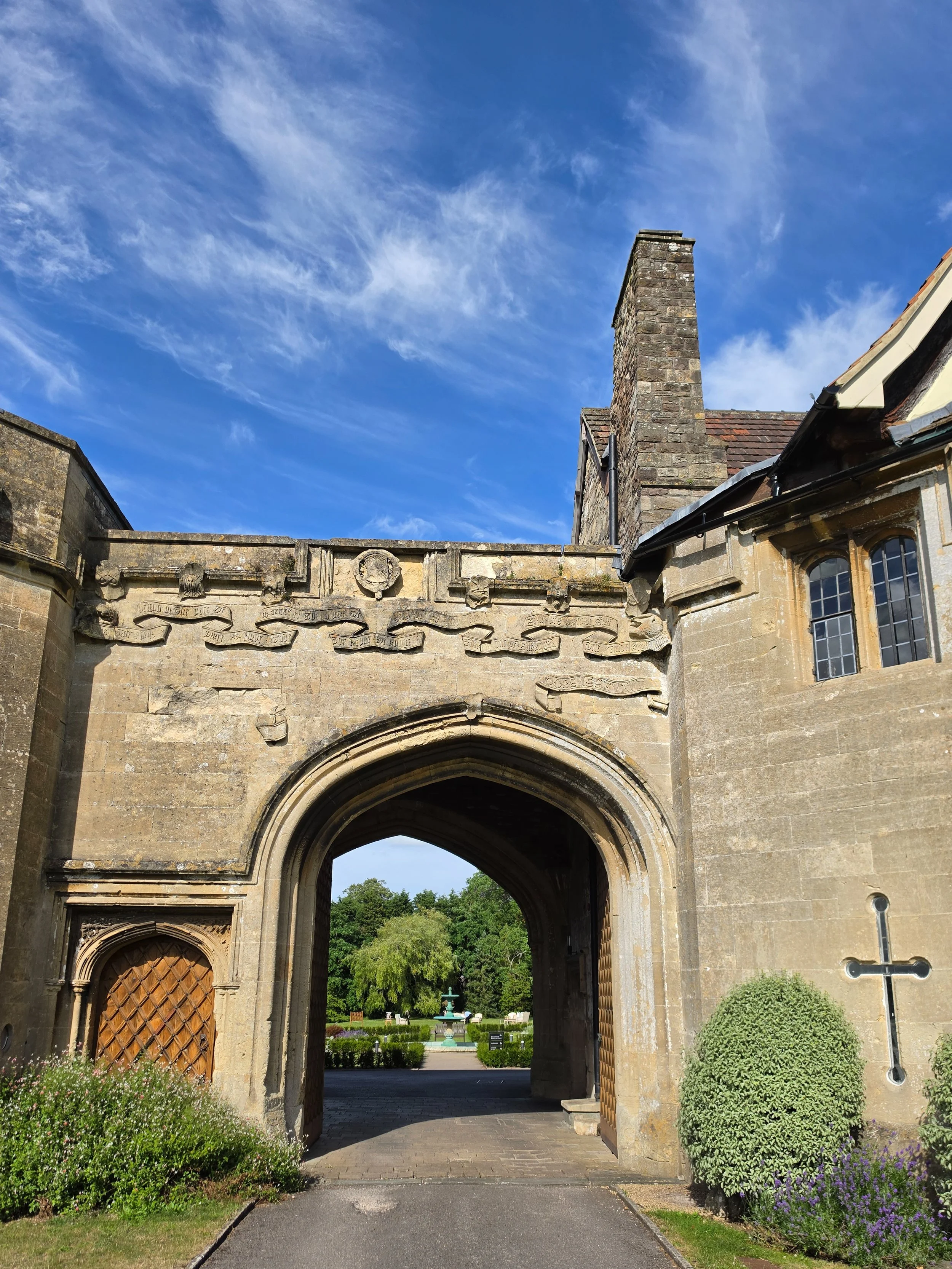 Historic castle entrance framed by medieval stone architecture and beautifully maintained gardens