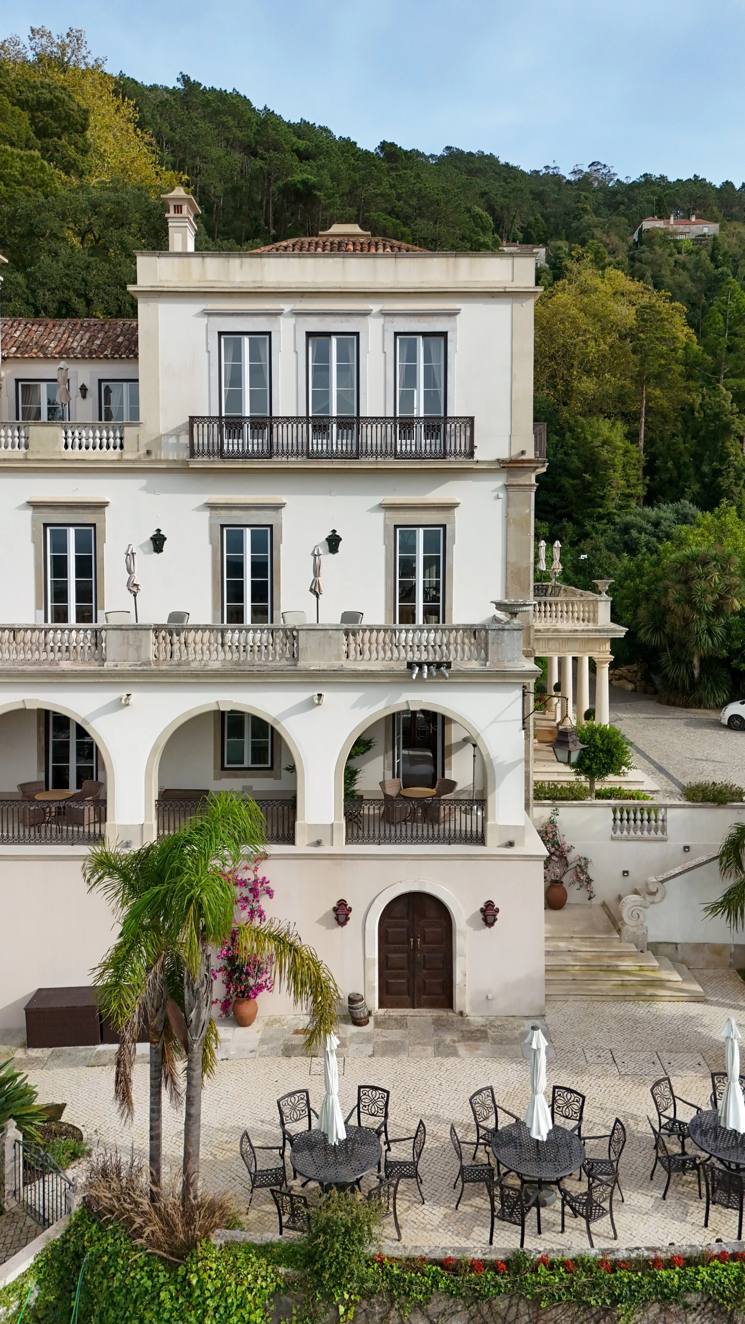 The historic white facade rises above garden terraces and forested Sintra hills
