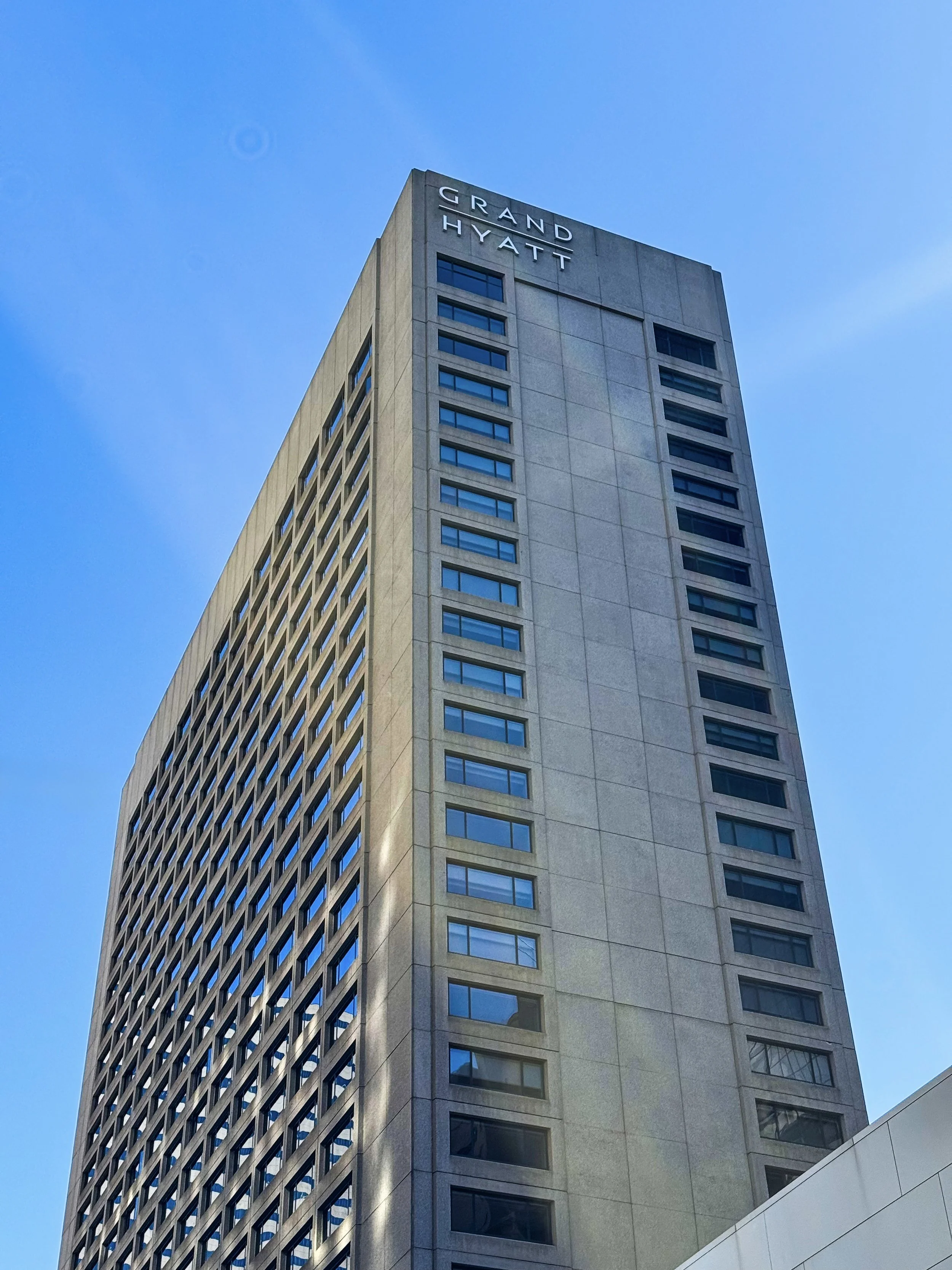 Exterior view of the Grand Hyatt Denver tower against a clear blue sky