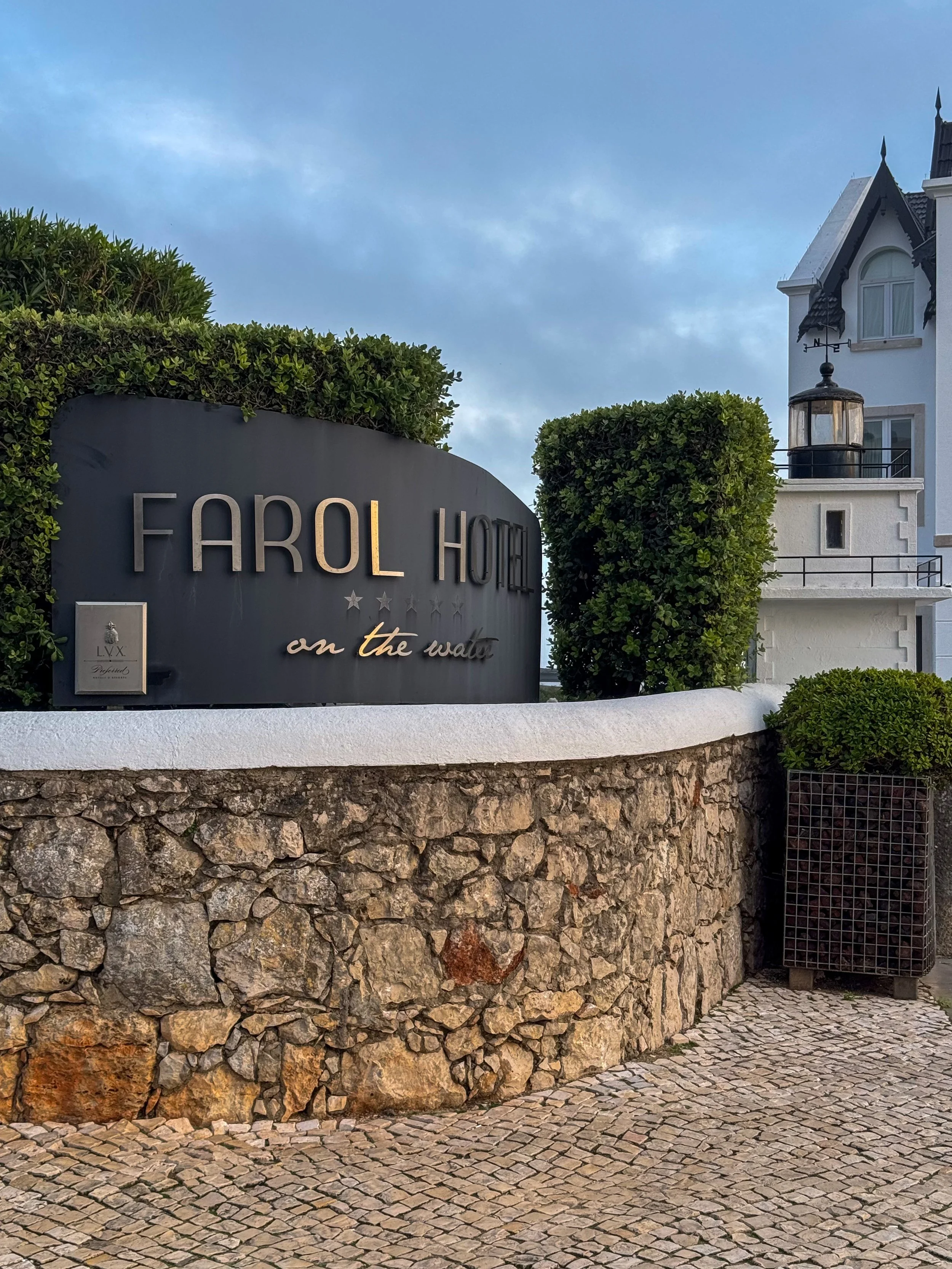 Farol Hotel entrance with signature signage beside the historic lighthouse in Cascais
