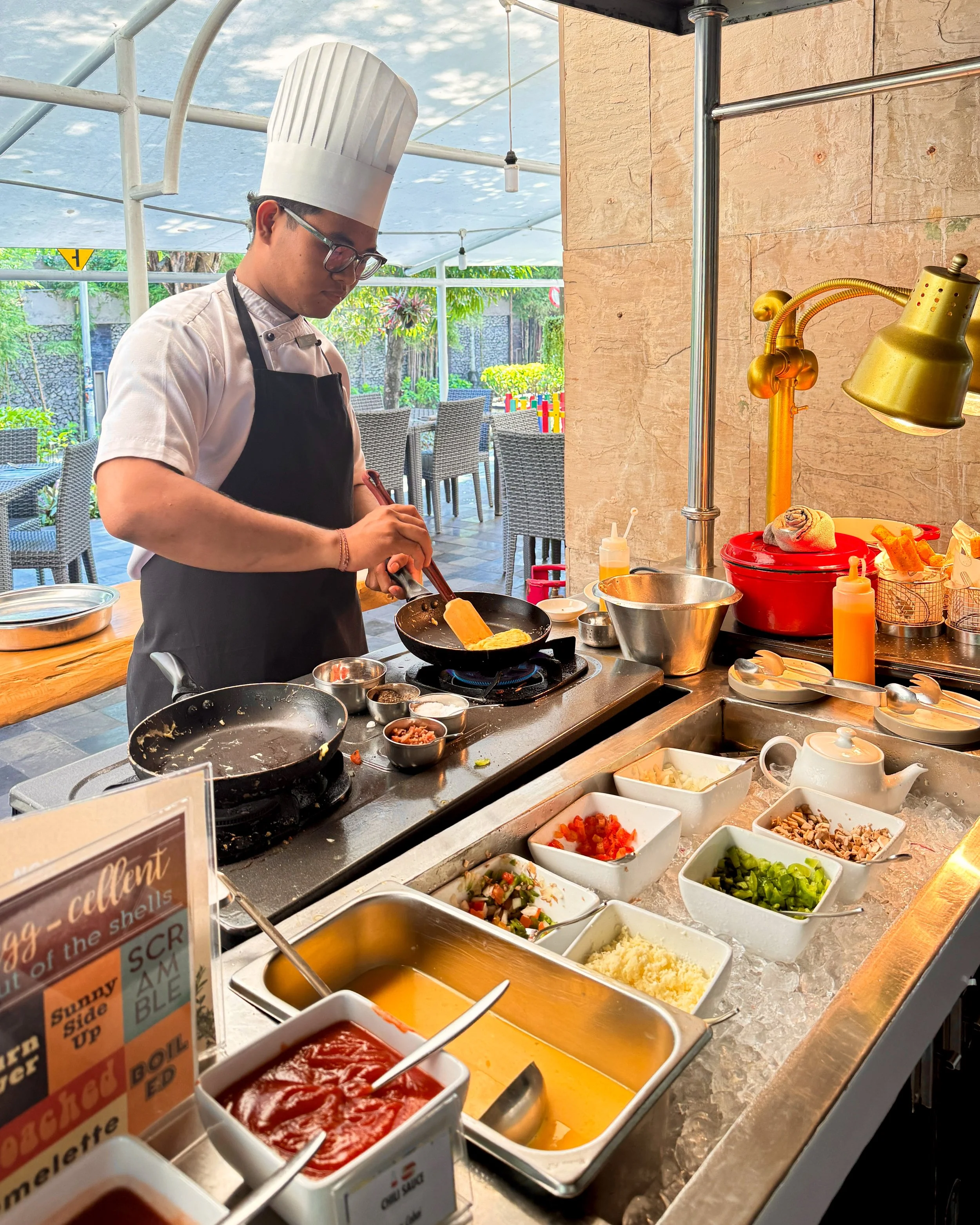 A chef prepares freshly made breakfast dishes at the live cooking station with a selection of seasonal ingredients