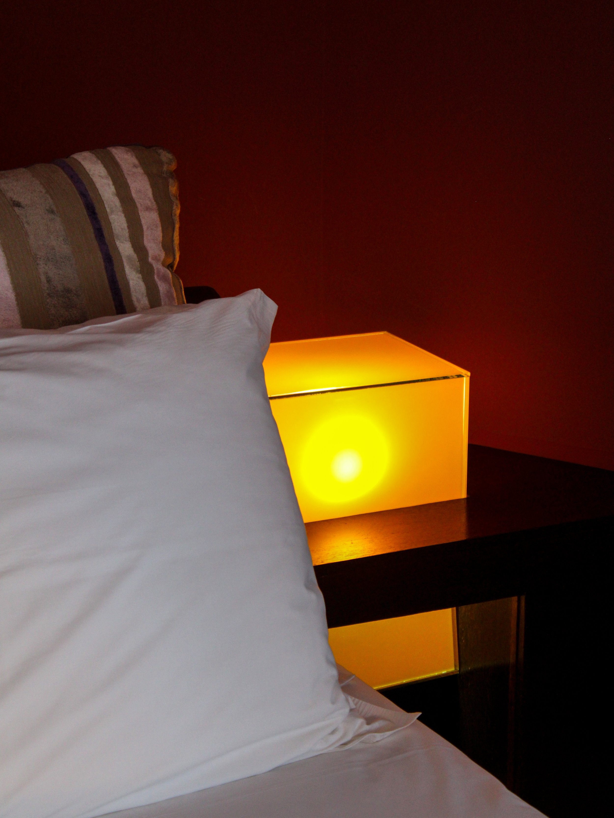 Minimalist bedside lighting creating a warm and relaxing atmosphere in a contemporary guest room