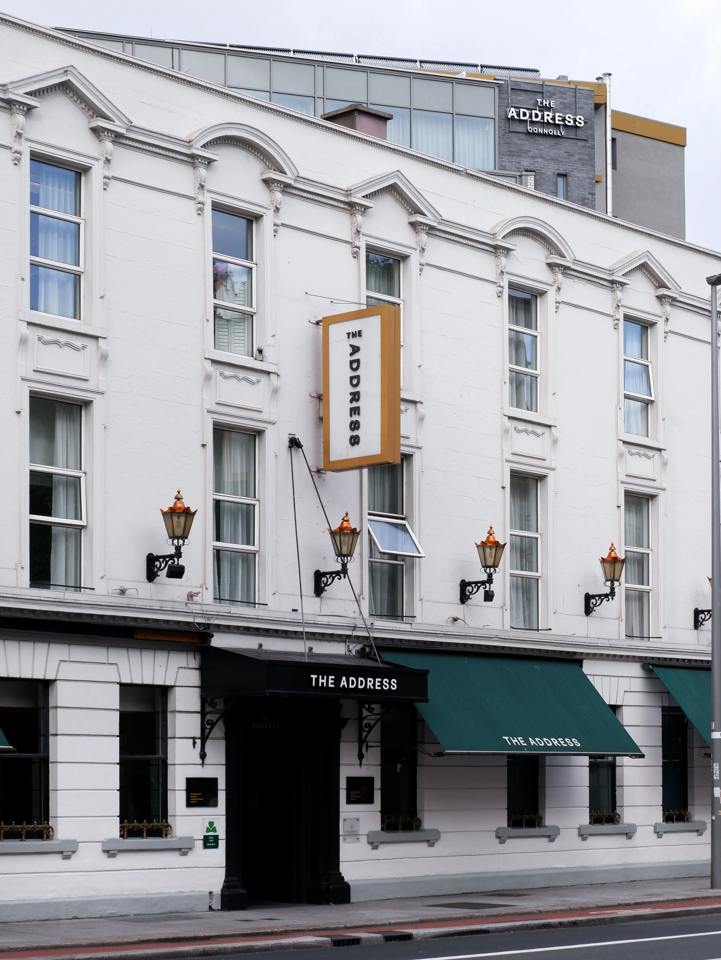 The Address Connolly exterior featuring a historic white facade, decorative windows, and green entrance awnings