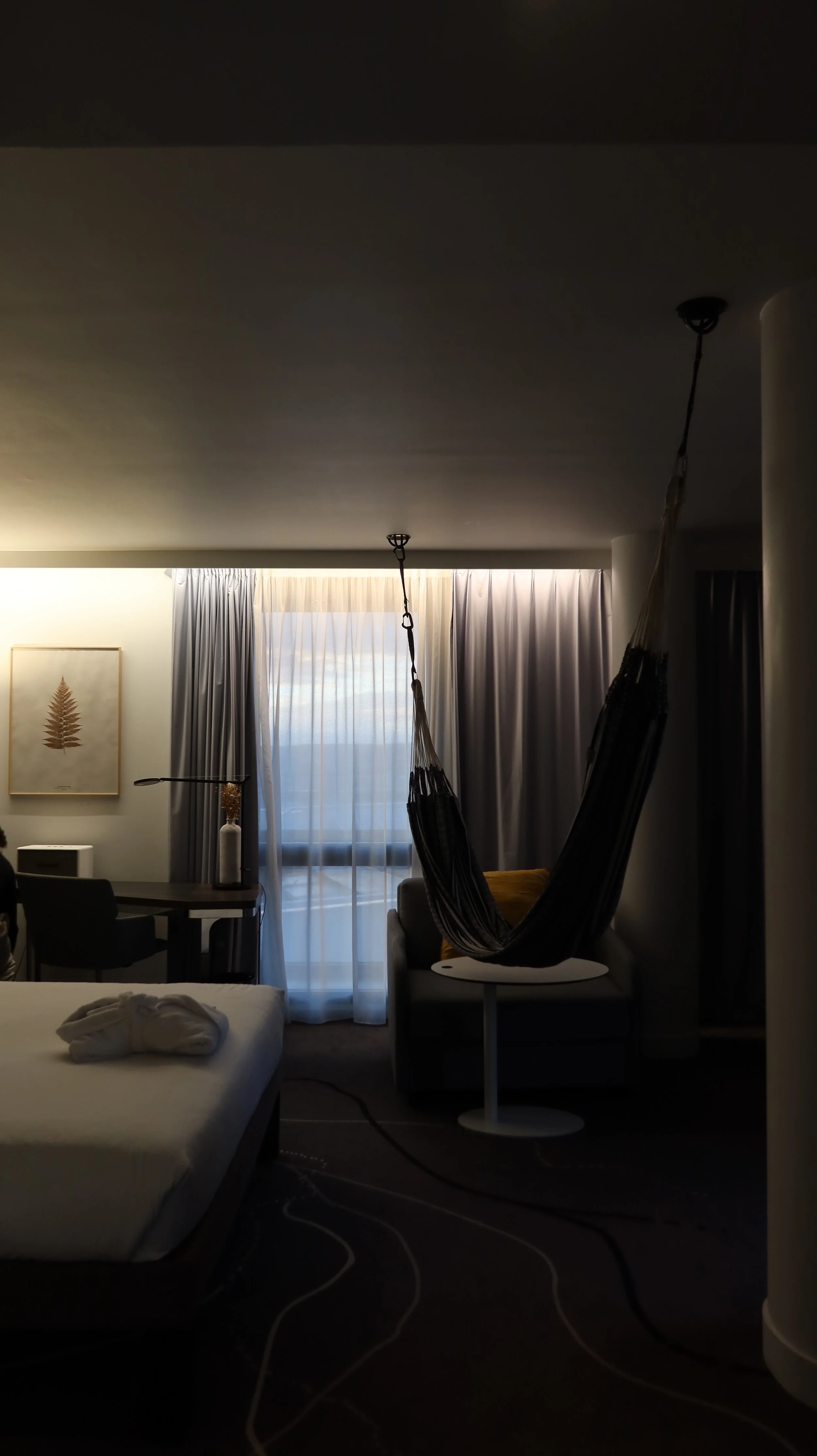 Cozy modern room with suspended hammock chair, soft ambient lighting, and minimalist workspace, Novotel Paris Porte de Versailles – Paris, France.