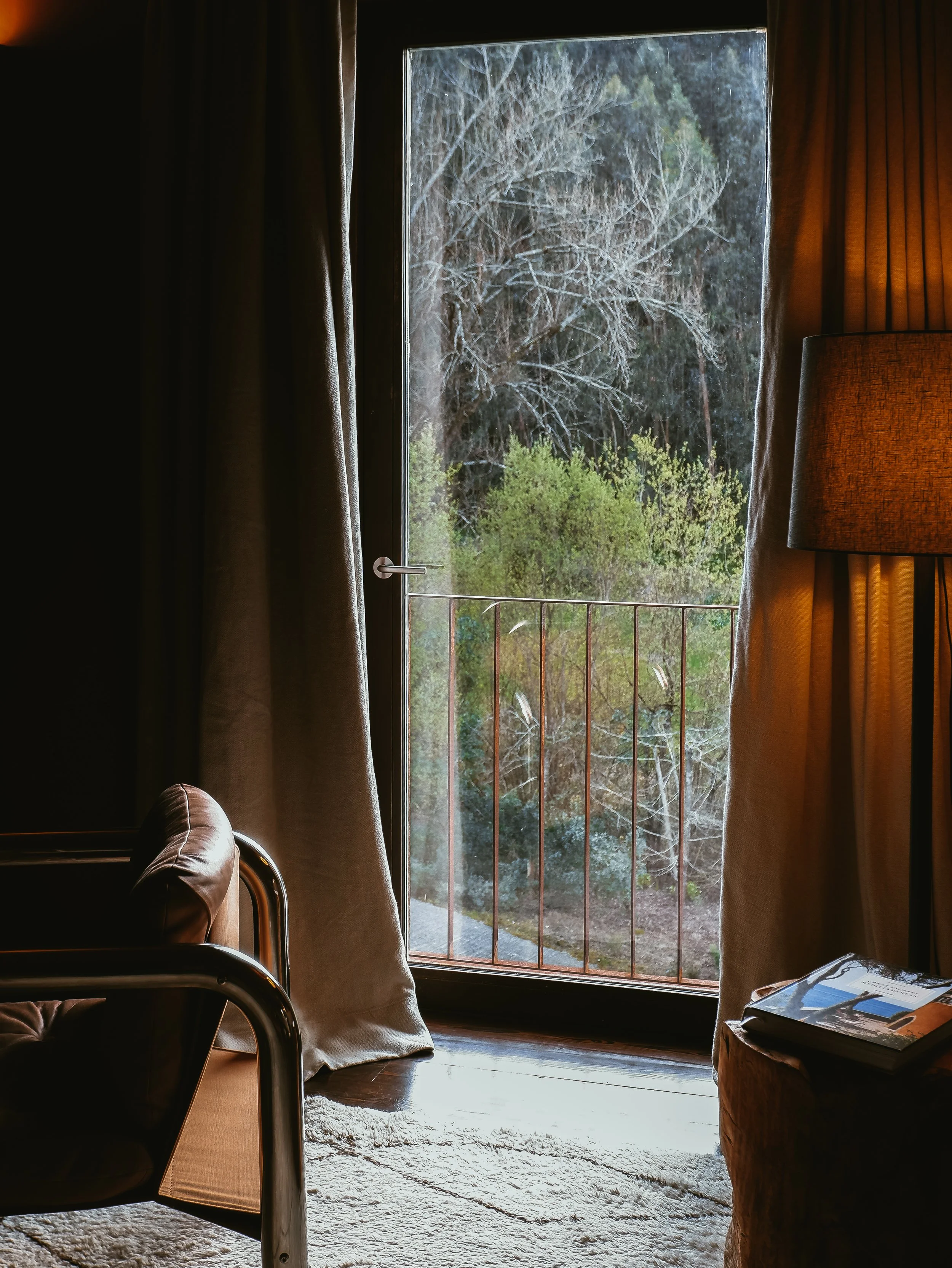 Cozy interior corner with warm lighting, natural textures, and forest views creating an intimate retreat atmosphere, Octant Douro – Castelo de Paiva, Portugal.