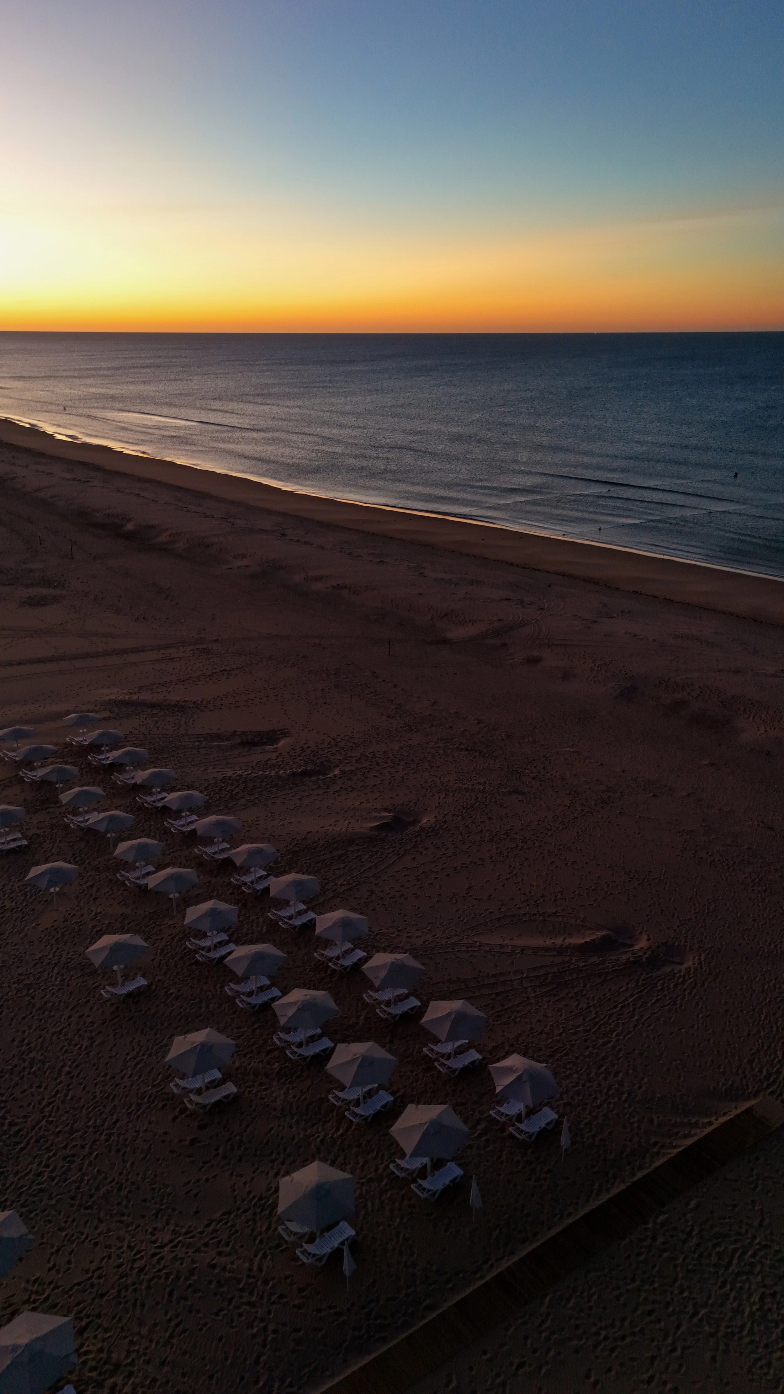 Sunrise over Monte Gordo Beach with reserved loungers overlooking the Atlantic Ocean