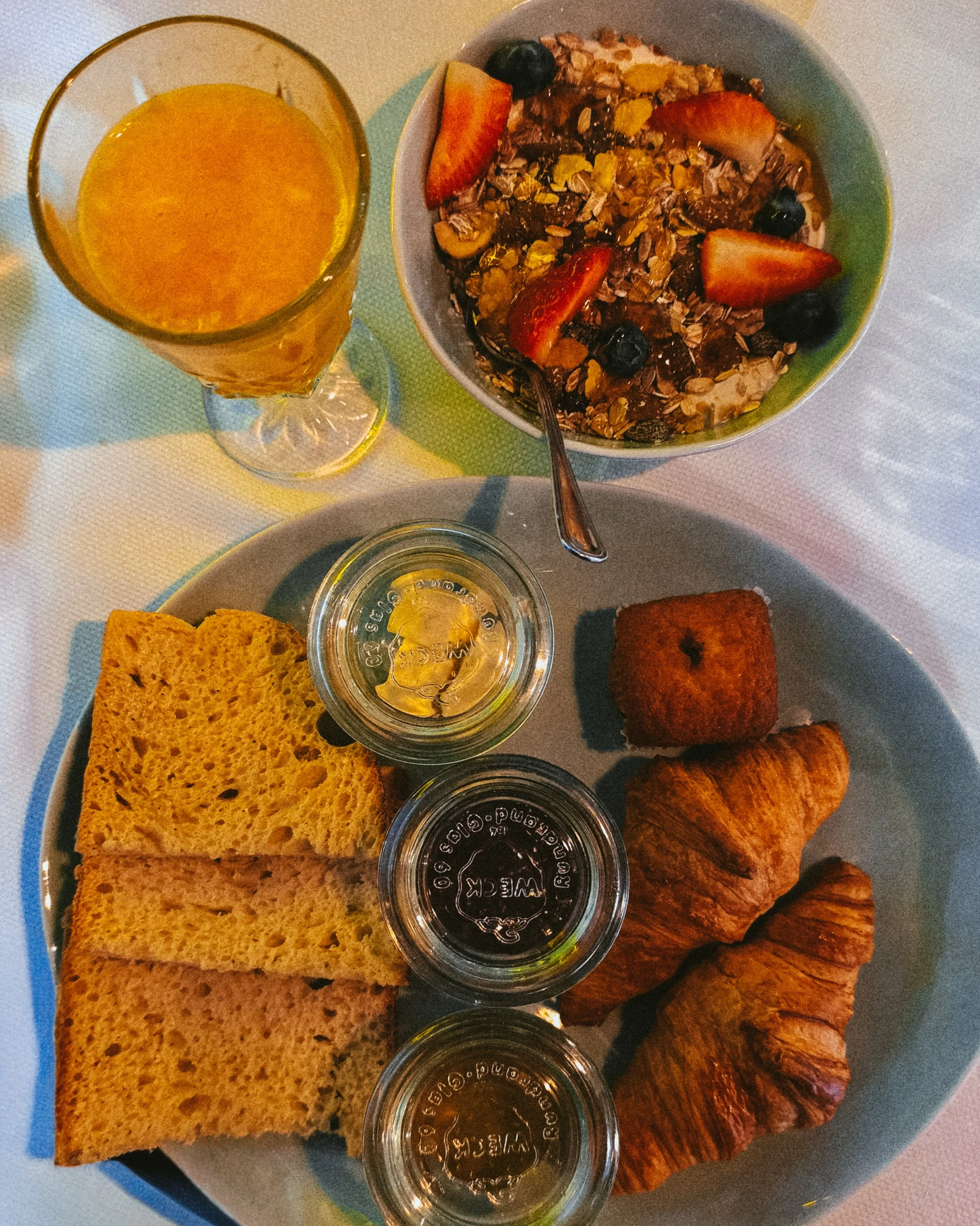 Fresh Mediterranean breakfast with homemade pastries, yogurt, seasonal fruit, granola, and fresh orange juice
