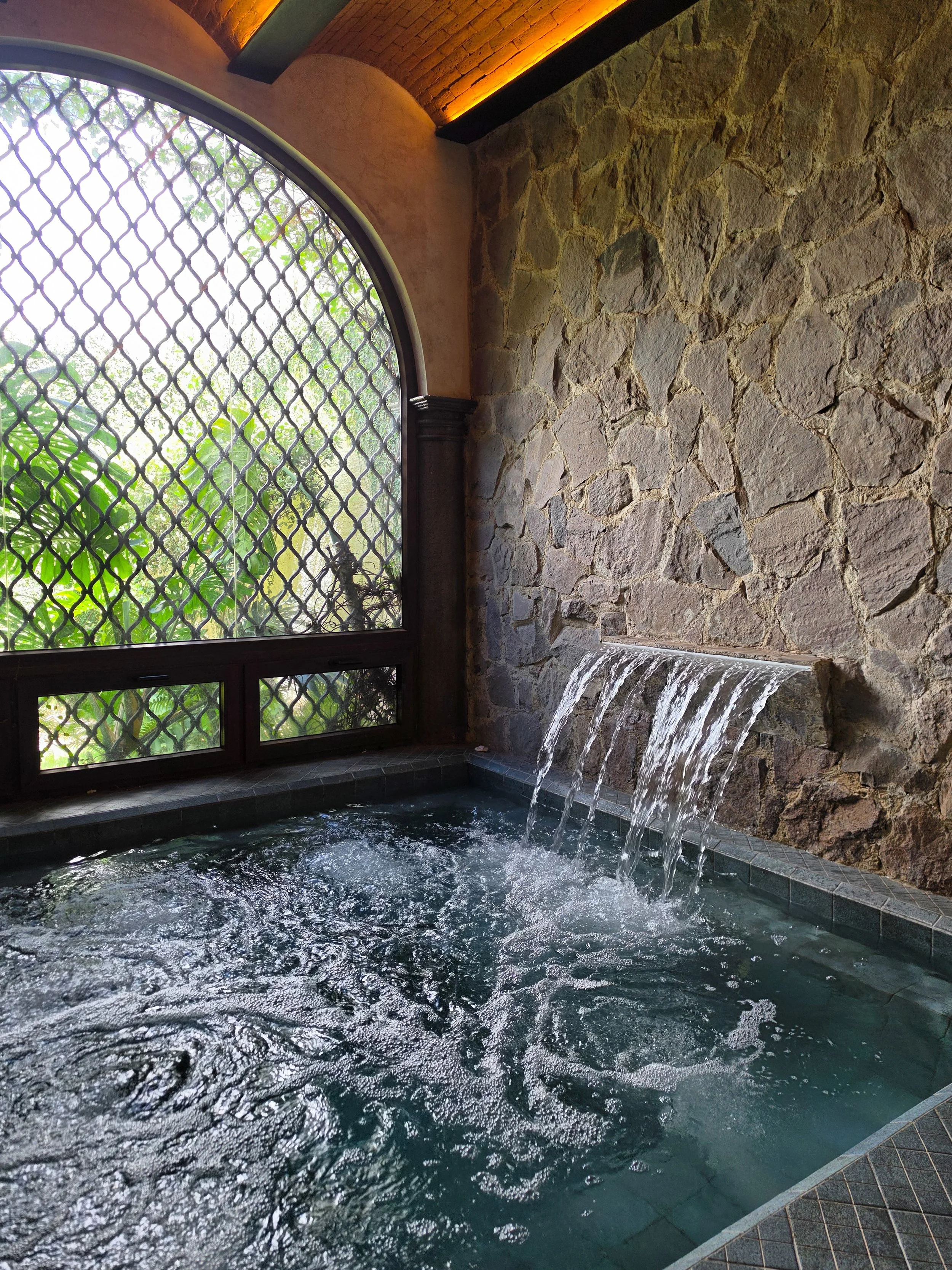 Indoor hydrotherapy pool surrounded by natural stone and warm lighting