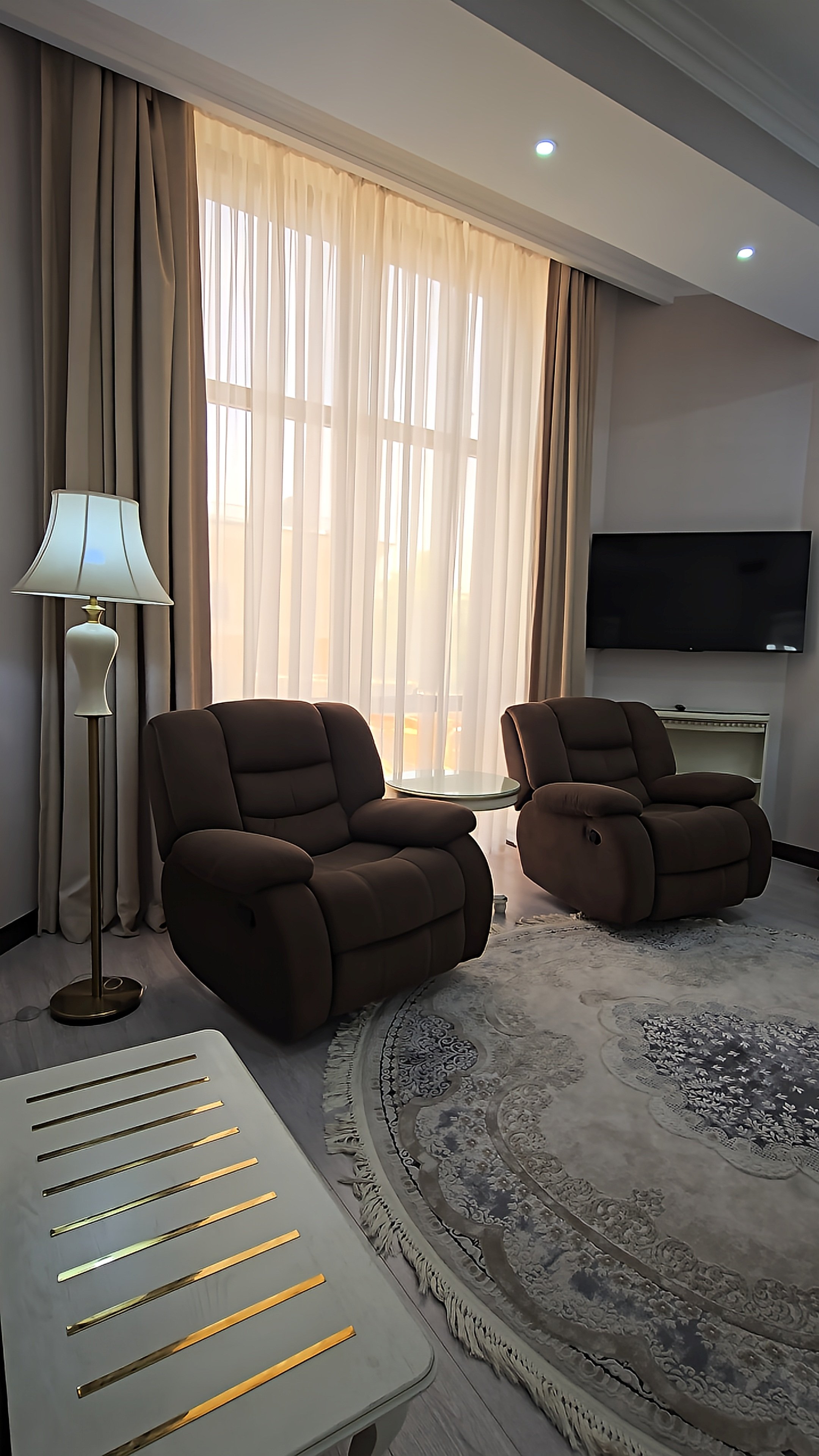 Spacious suite lounge with reclining armchairs, soft natural light and refined interiors at Dilimah Premium Luxury Hotel