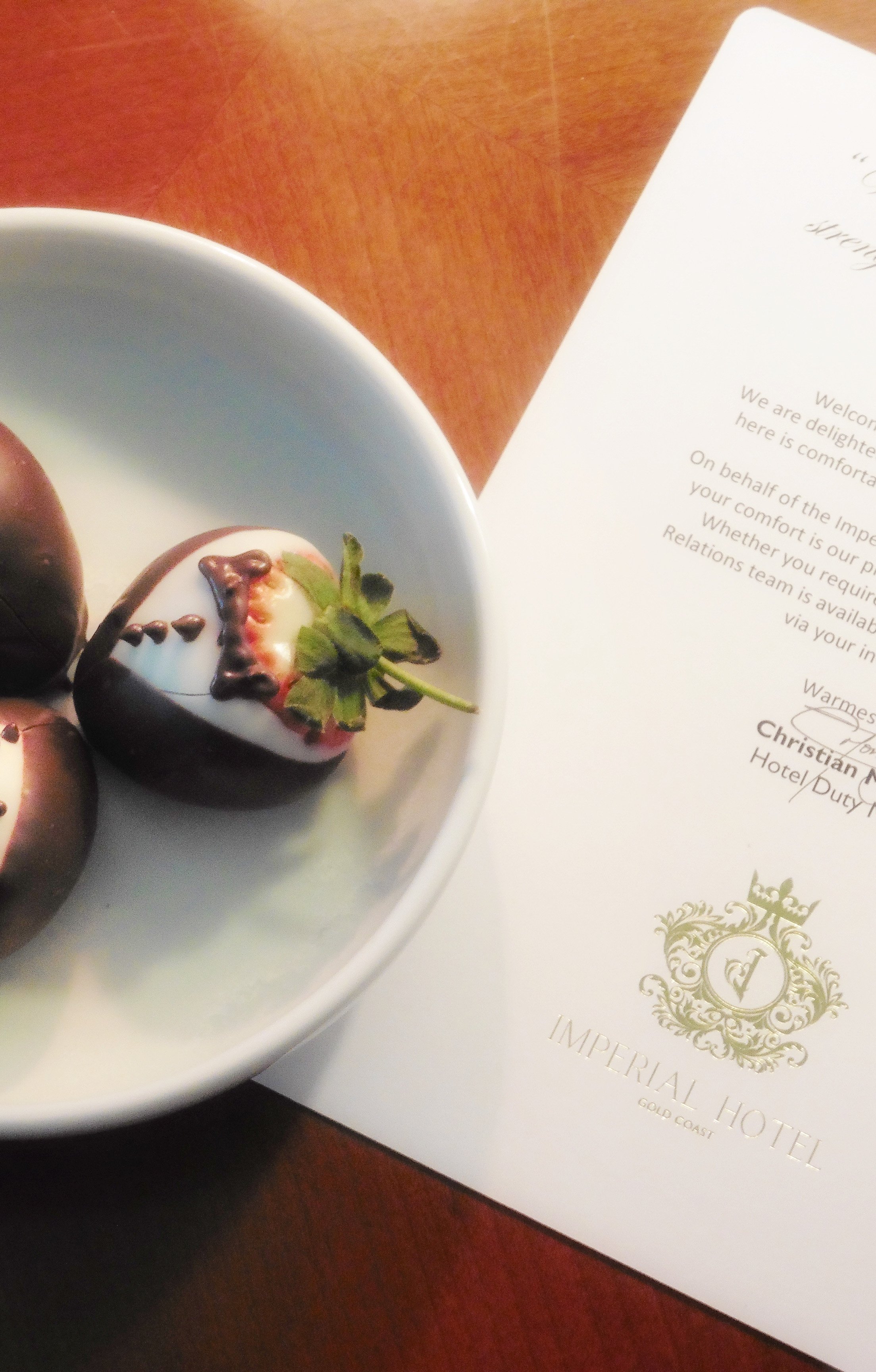 Personalized welcome amenity featuring chocolate-covered strawberries and a handwritten guest letter at Imperial Hotel Gold Coast