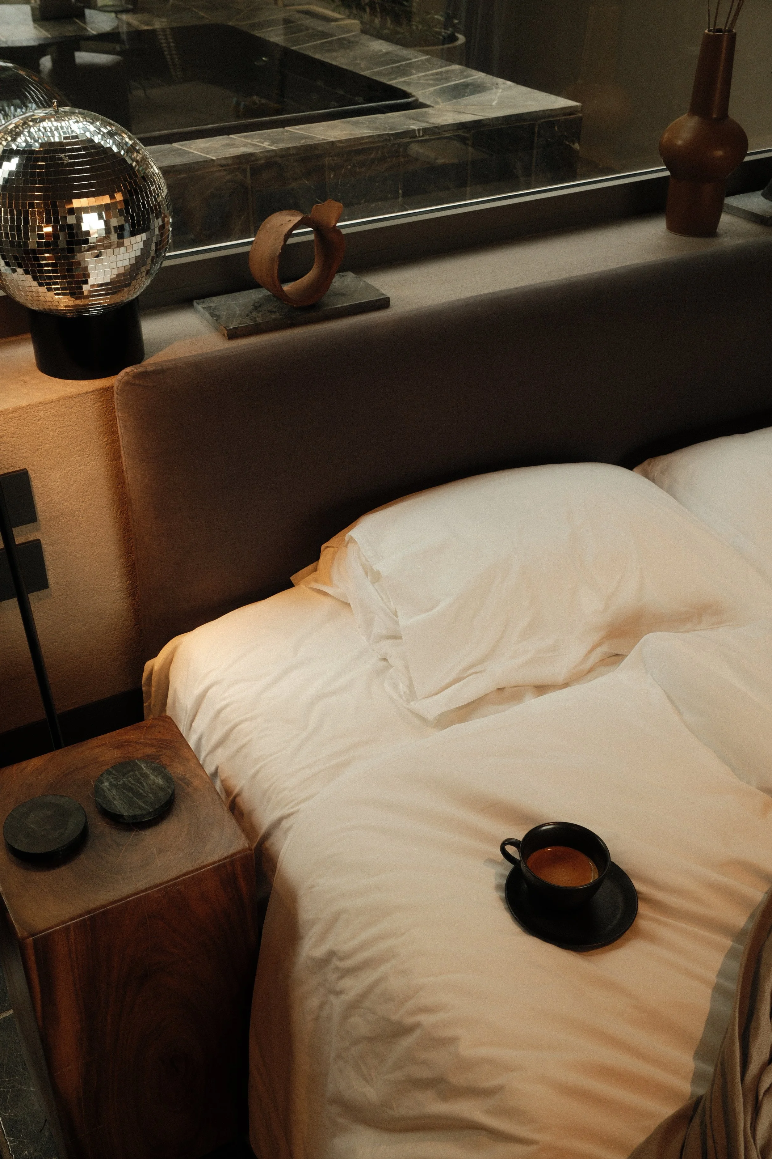 Boutique bedroom with crisp white bedding, warm wood details, and a coffee served in bed