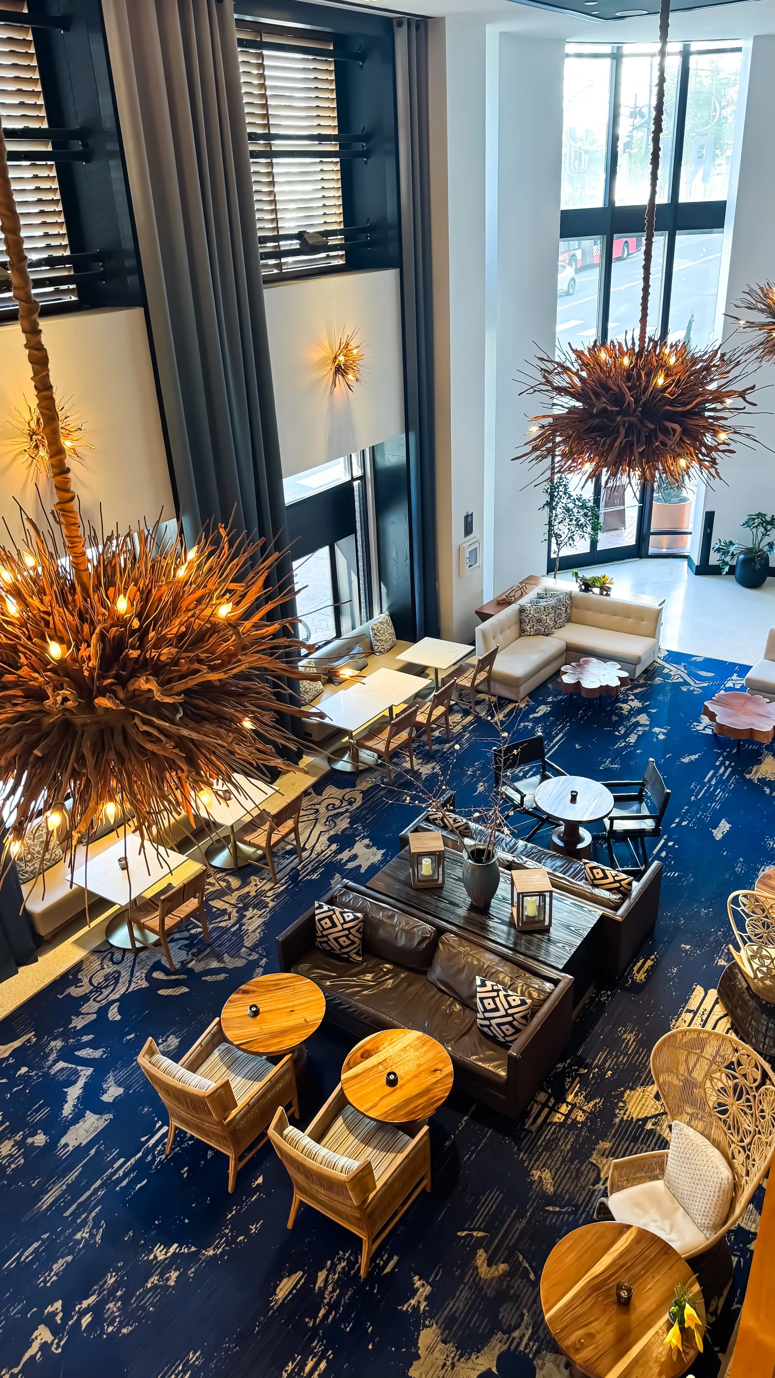 Double-height lobby with sculptural wood chandeliers, modern seating, and natural light flooding through tall windows, Hotel Republic San Diego – San Diego, California.