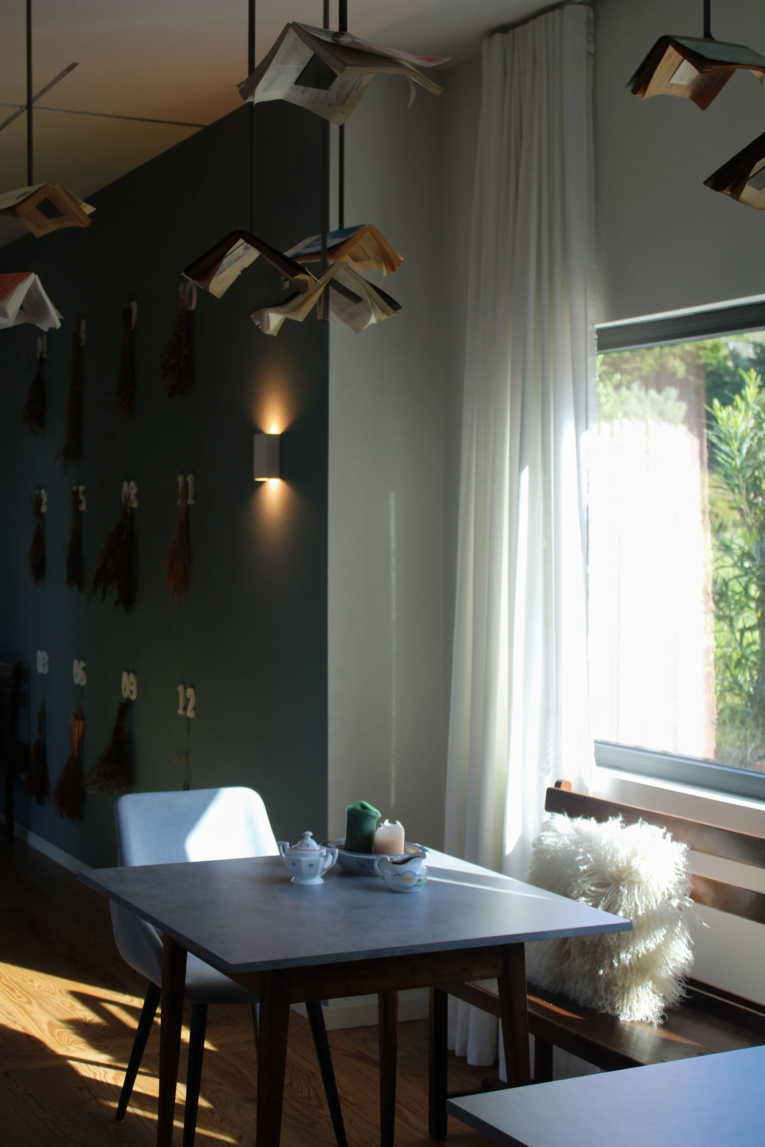 Sunlit dining corner with warm tones and unique suspended book decor at Dream Guincho