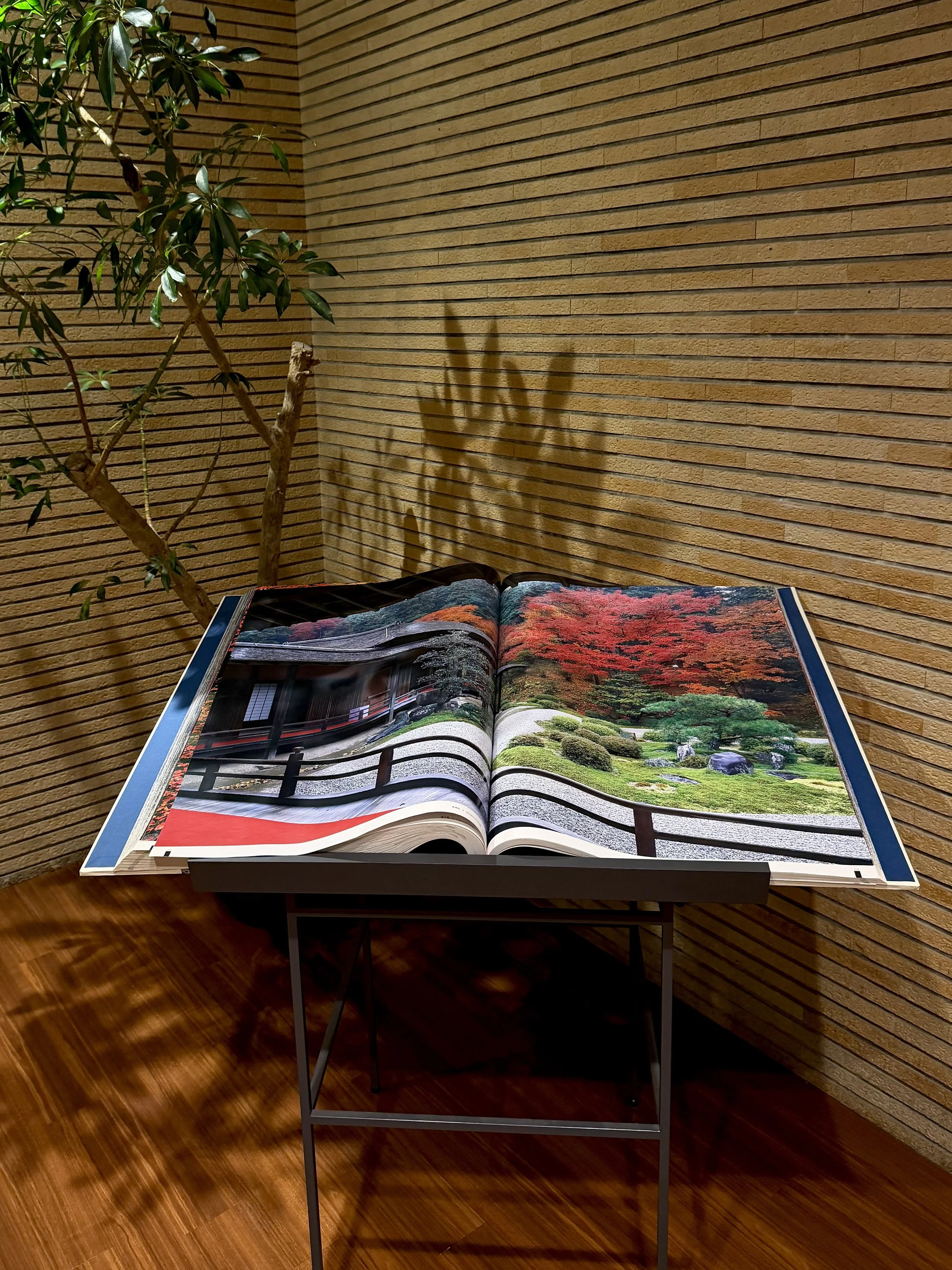 Open photography book showcasing a Japanese garden surrounded by warm wood and natural greenery