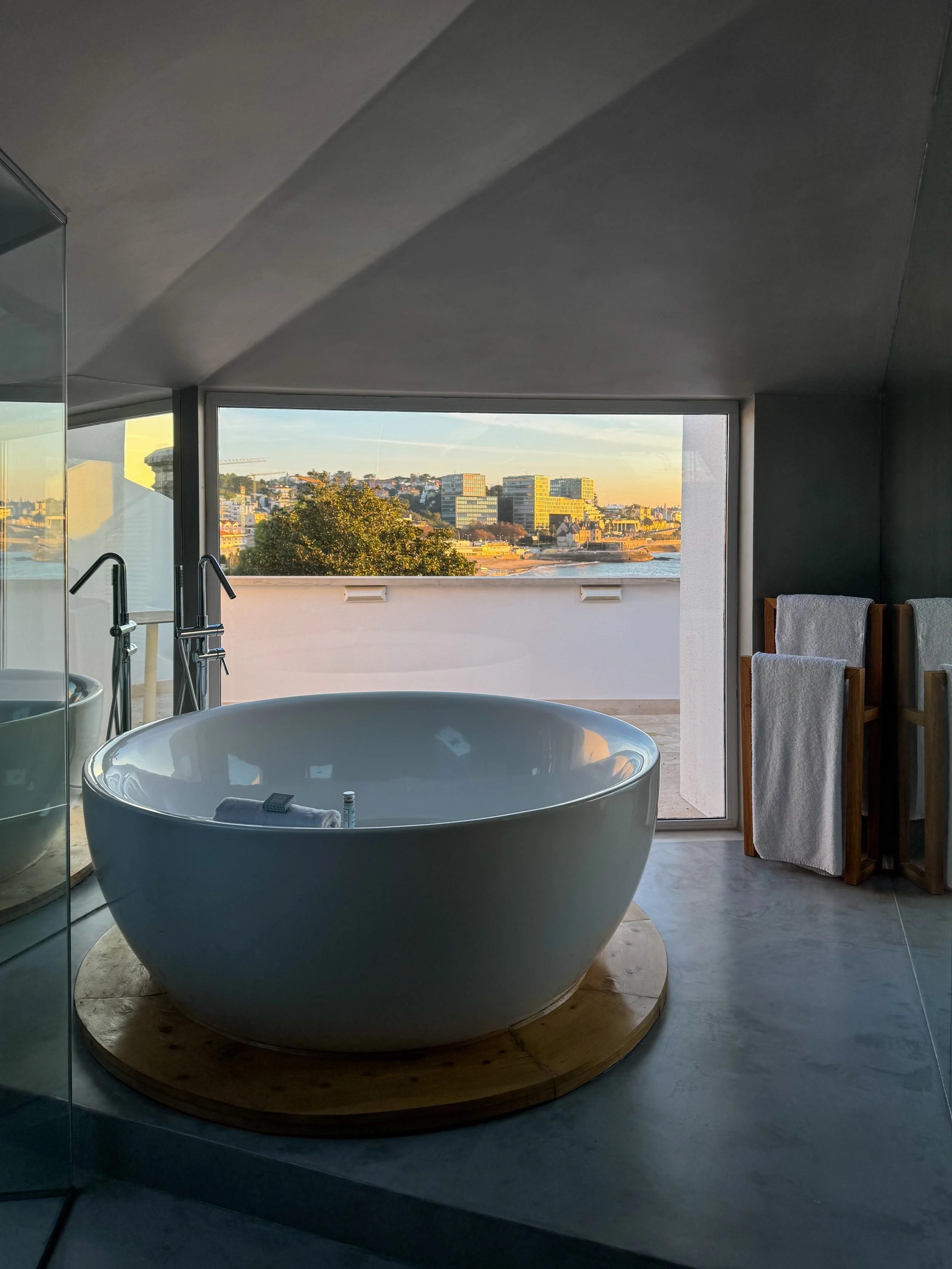 Freestanding bathtub with panoramic views across Cascais Bay from a luxury suite