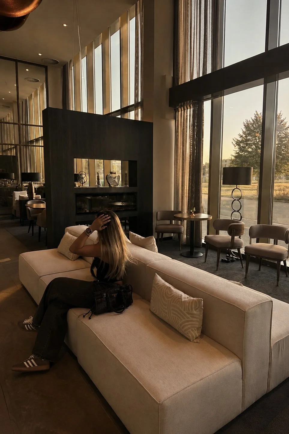 Warm lounge space with fireplace and floor-to-ceiling windows at sunset