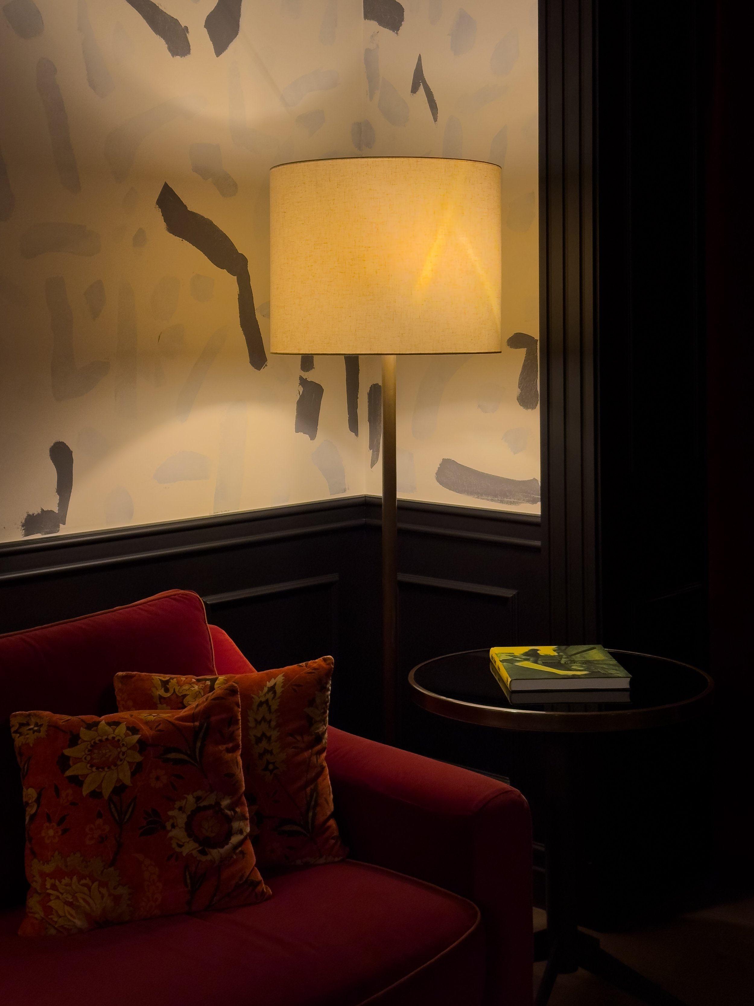 Warm reading corner with velvet armchair and designer lighting inside Wittmore Hotel