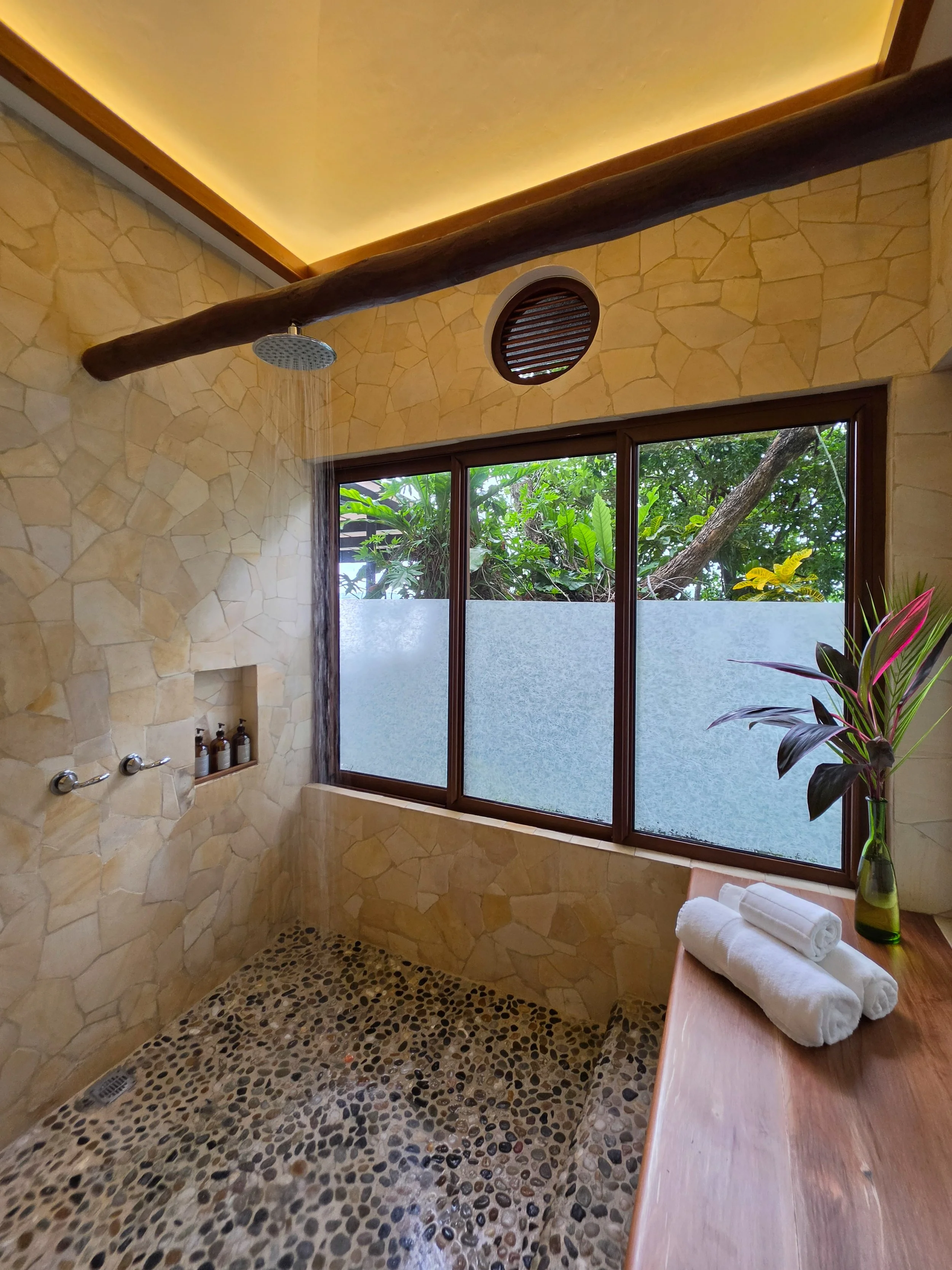 Nature-inspired rain shower with stone finishes and lush garden views